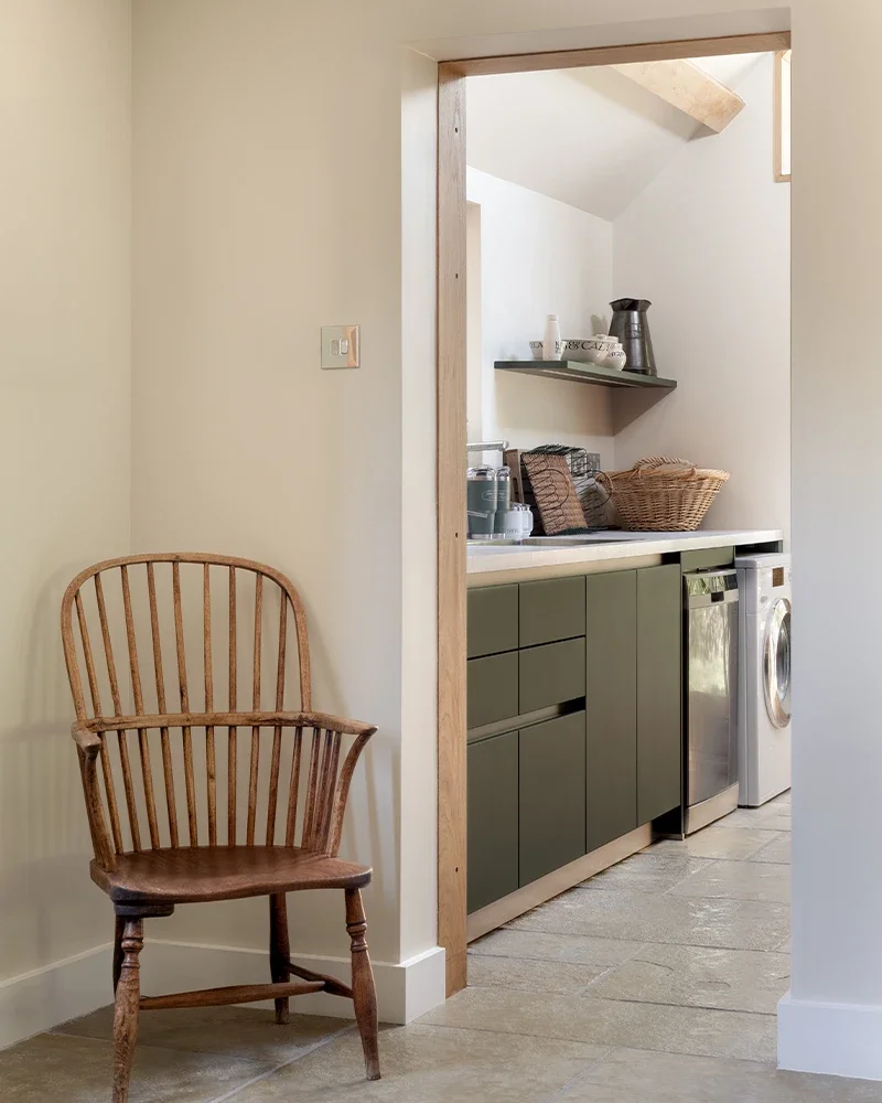 Forest green utility room adjoining the open-plan living space