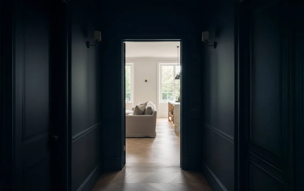 Dark painted corridor into light white room