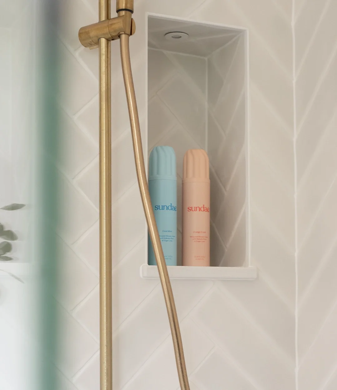 White herringbone tiled shower with brushed brass fixtures.