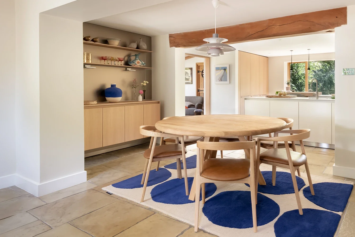 Country home dining area with exposed beam and bulthaup kitchen beyond