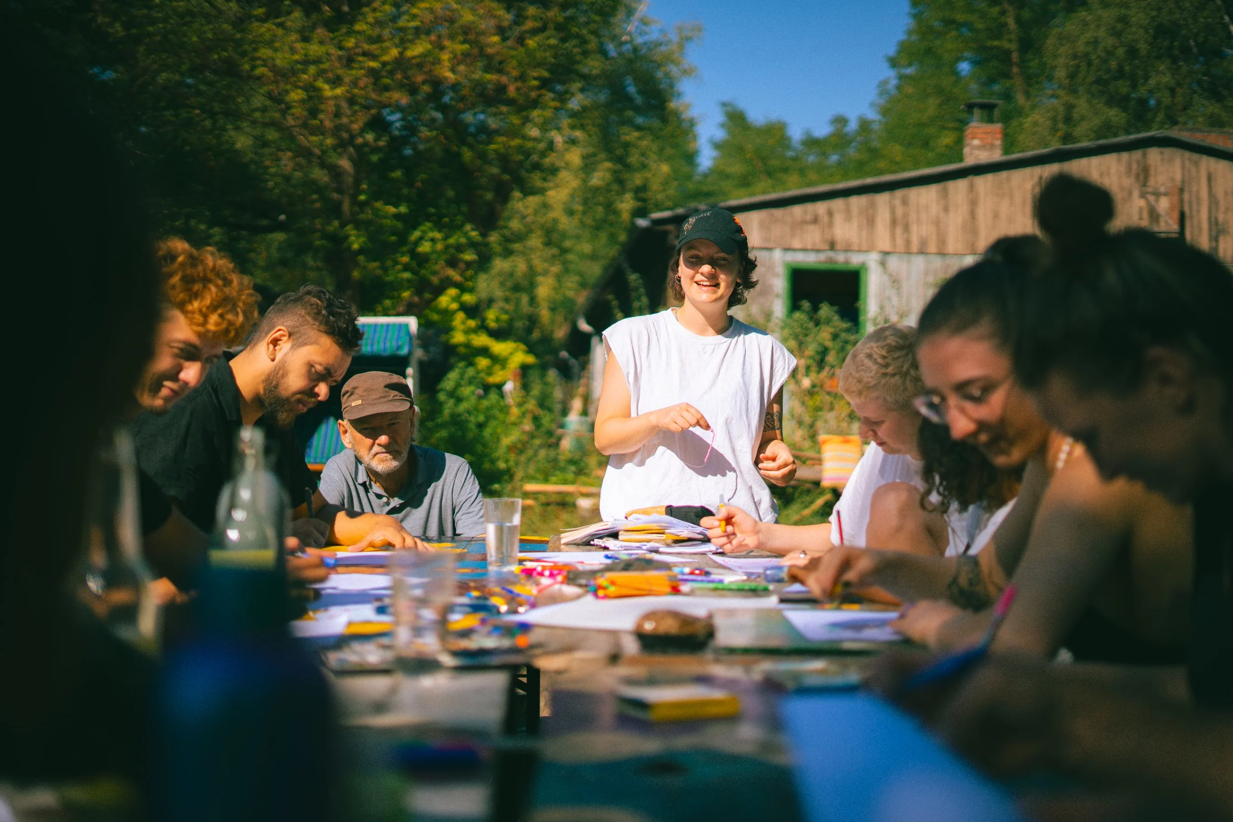 Personen sitzen um einen Tisch und malen