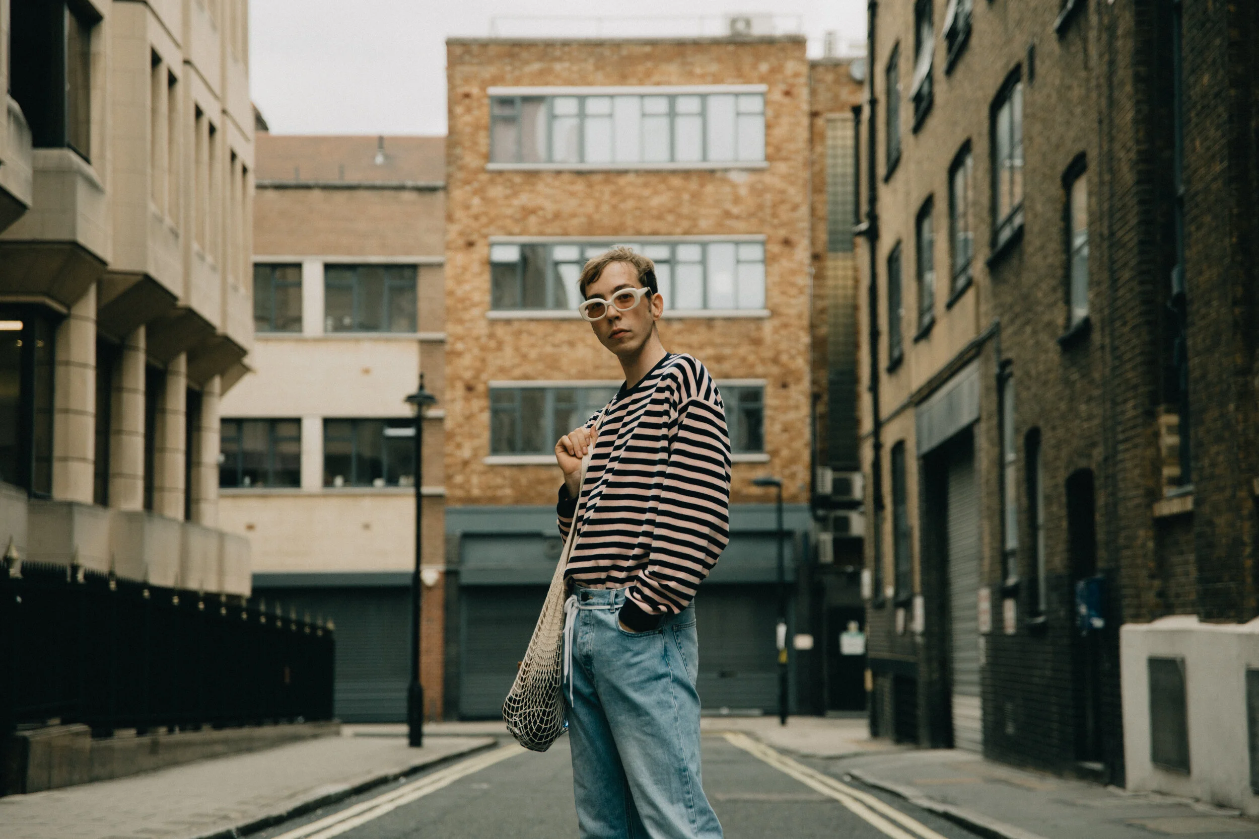 Young man attending London Fashion Week. Street Style, man wearing striped shirt and jeans.