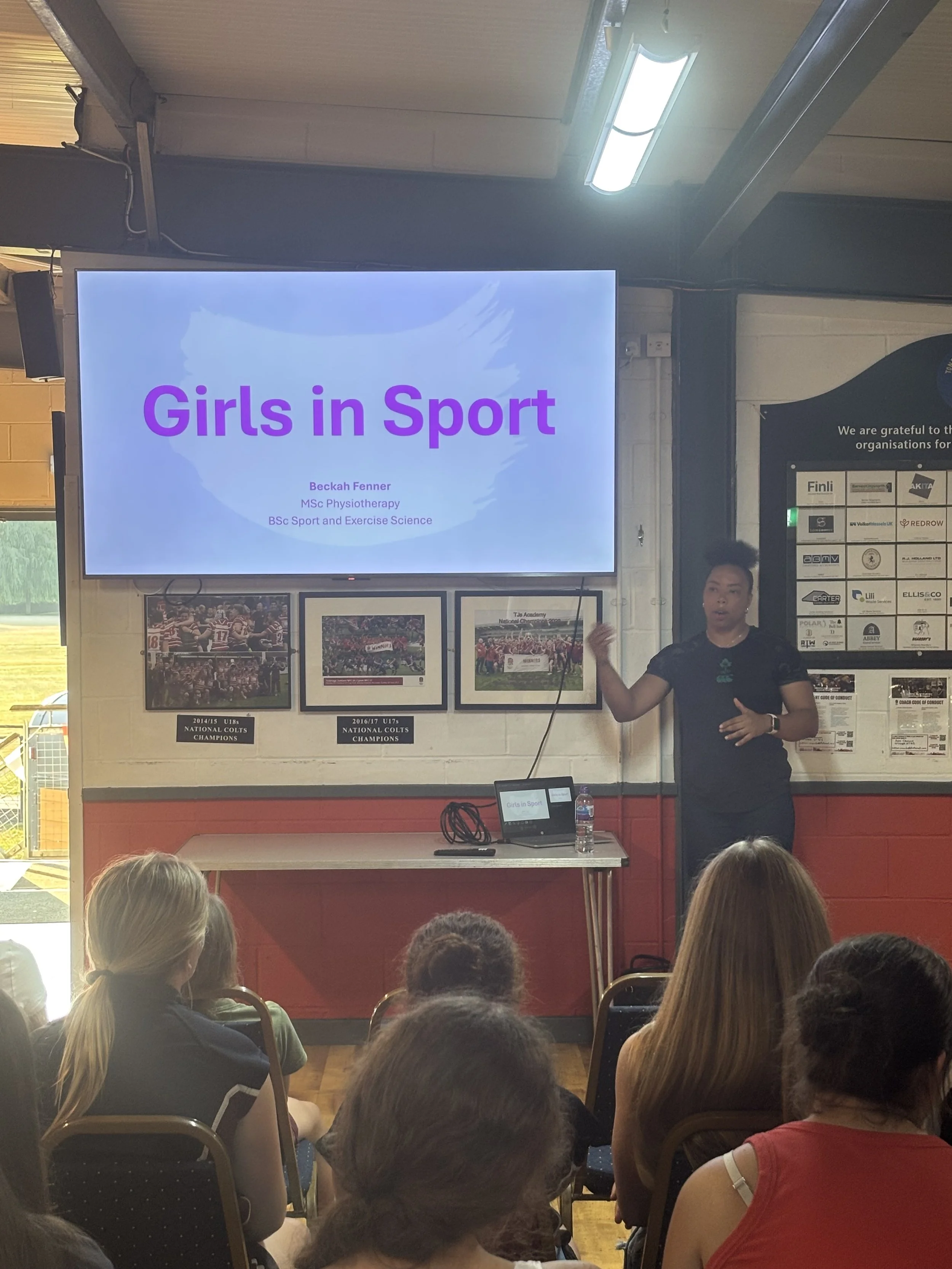 Ireland rugby union player Grace Moore speaking next to a screen which says Girls in Sport at TJ's rugby club in Kent.