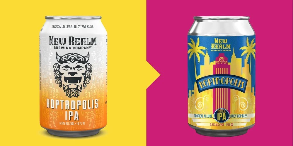 Two beer cans from New Realm Brewing Company, both labeled "Hoptropolis IPA." The left can has a yellow and orange gradient with a mythical lion head design. The right can features a colorful cityscape with palm trees on a yellow and magenta backgrou