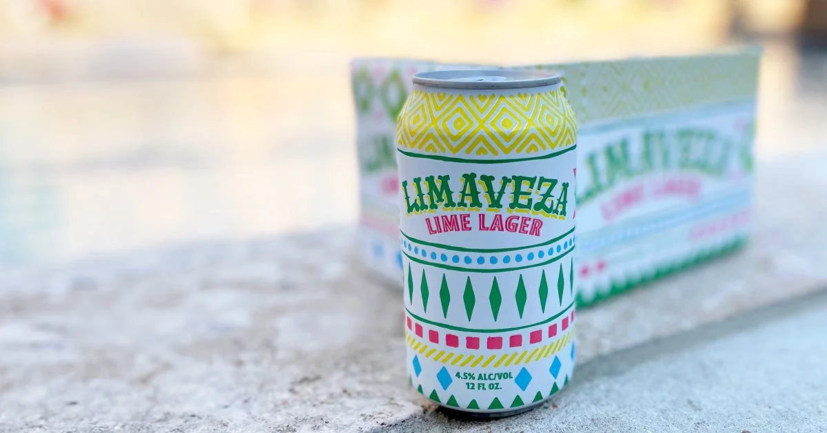Limaveza Lime Lager beer can with a colorful design, featuring geometric patterns, and a 4.5% alcohol content indication, placed against a blurred background of a 12-pack box.