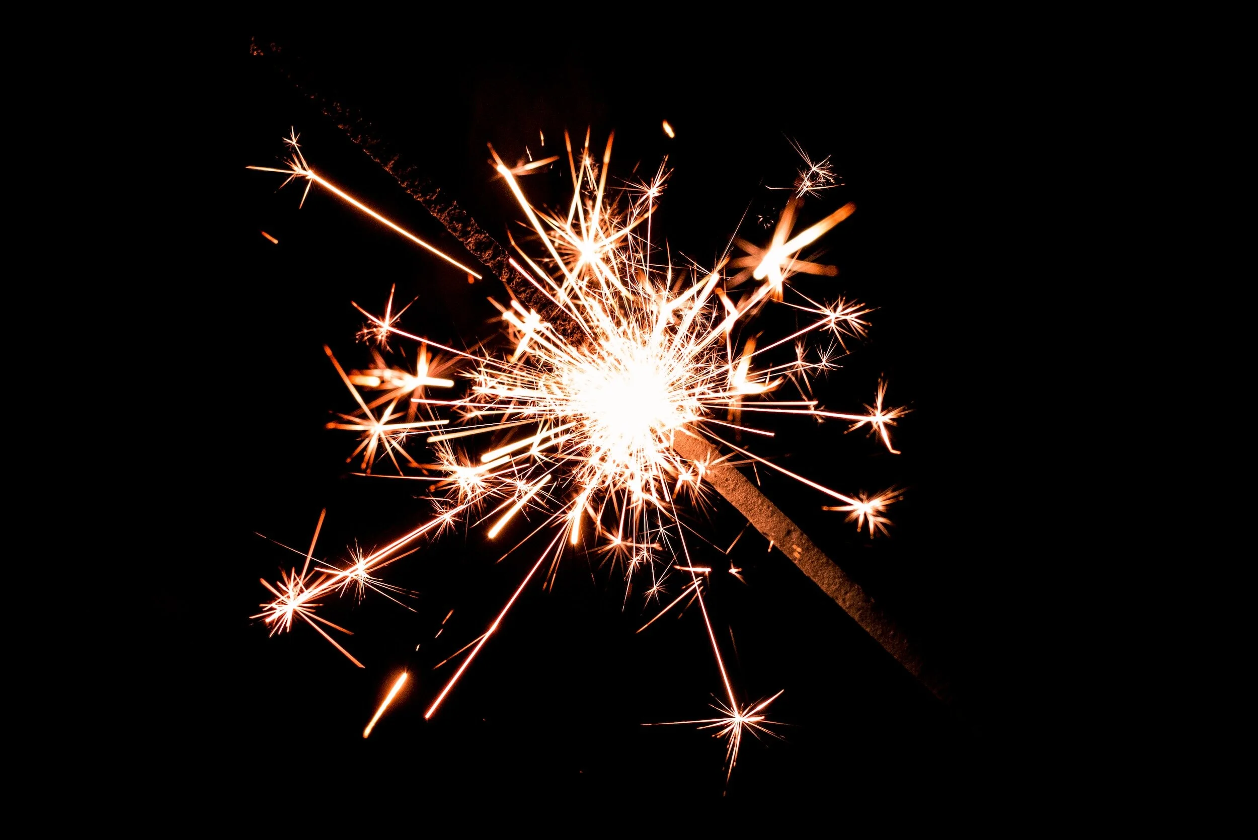 Sparkler burning with bright sparks against a dark background.