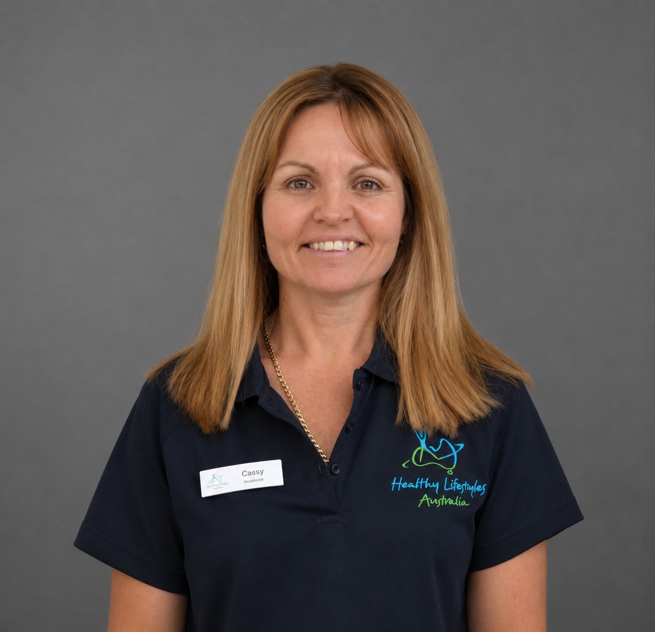 Smiling woman in a navy blue polo shirt with "Healthy Lifestyles Australia" logo.