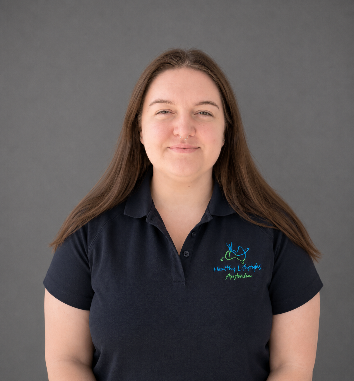 Person wearing a black polo shirt with "Healthy Lifestyles Australia" logo, standing against a textured wall.