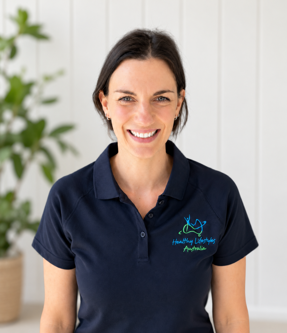 A woman with short dark hair smiling at the camera, wearing a navy polo shirt with a logo that reads 'Healthy Lifestyles Australia'.