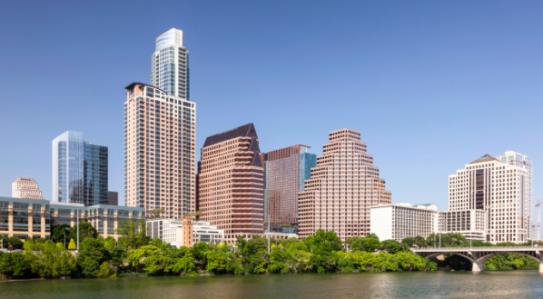 Skyline of downtown city with high-rise buildings and a river in the foreground.