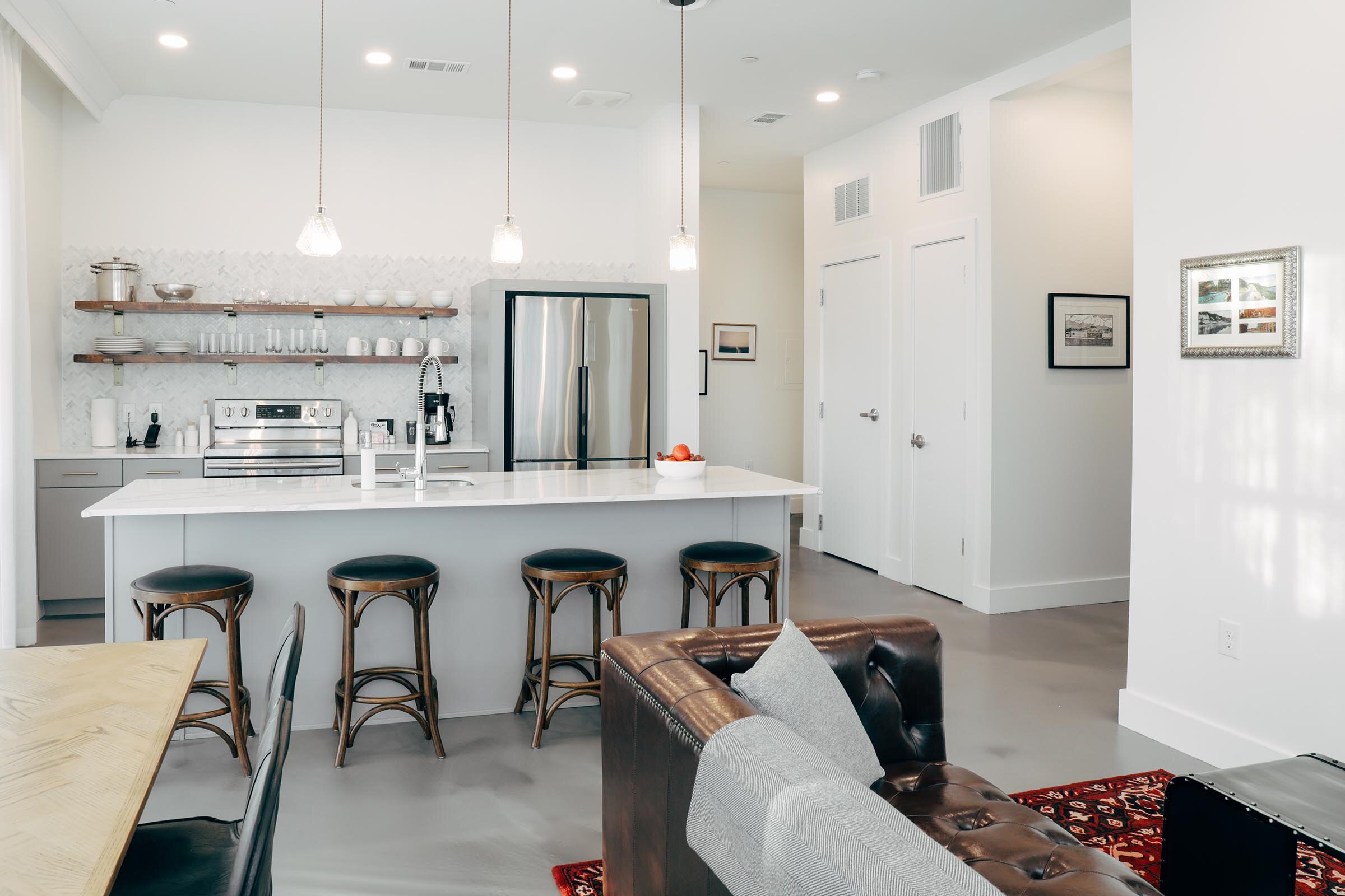 kitchen with breakfast bar and stools, partial view of dining table, living area (Copy)