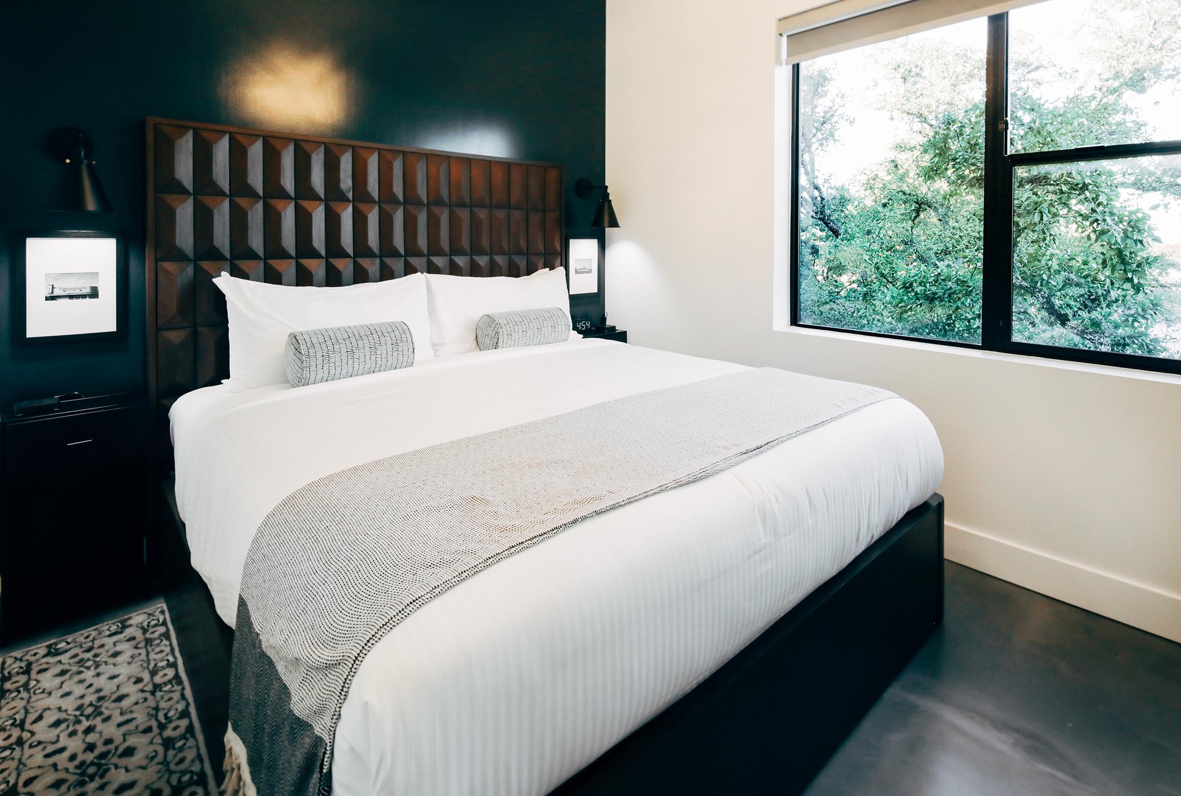 king bed with dark wooden headboard against dark blue wall