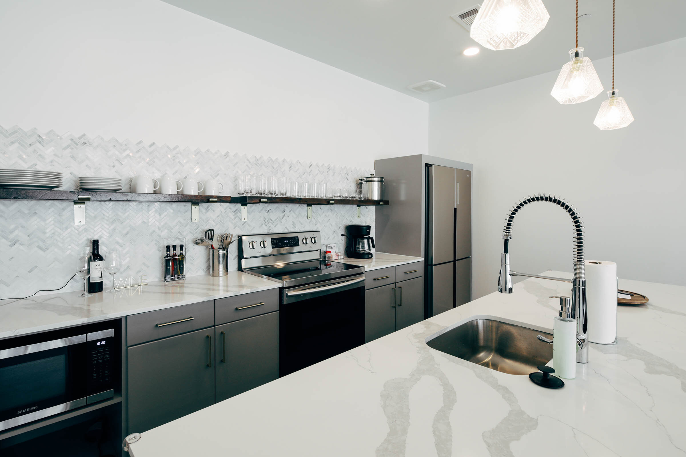 Full kitchen with fridge, oven, exposed shelves with dishware