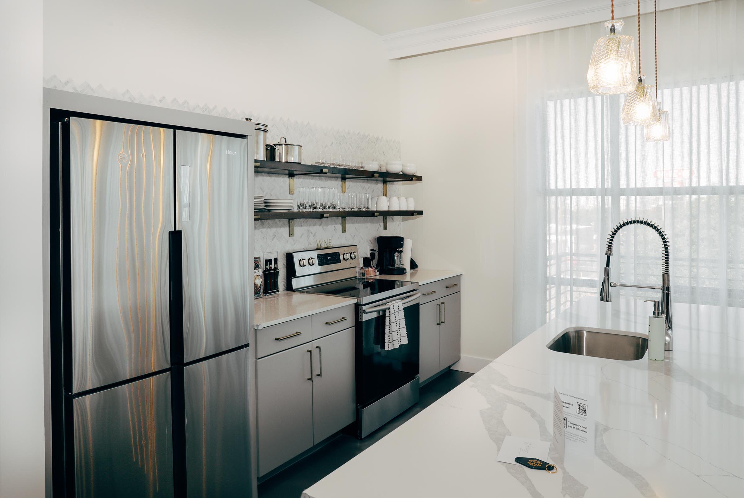 Full kitchen with exposed shelves with dishware, white counterops