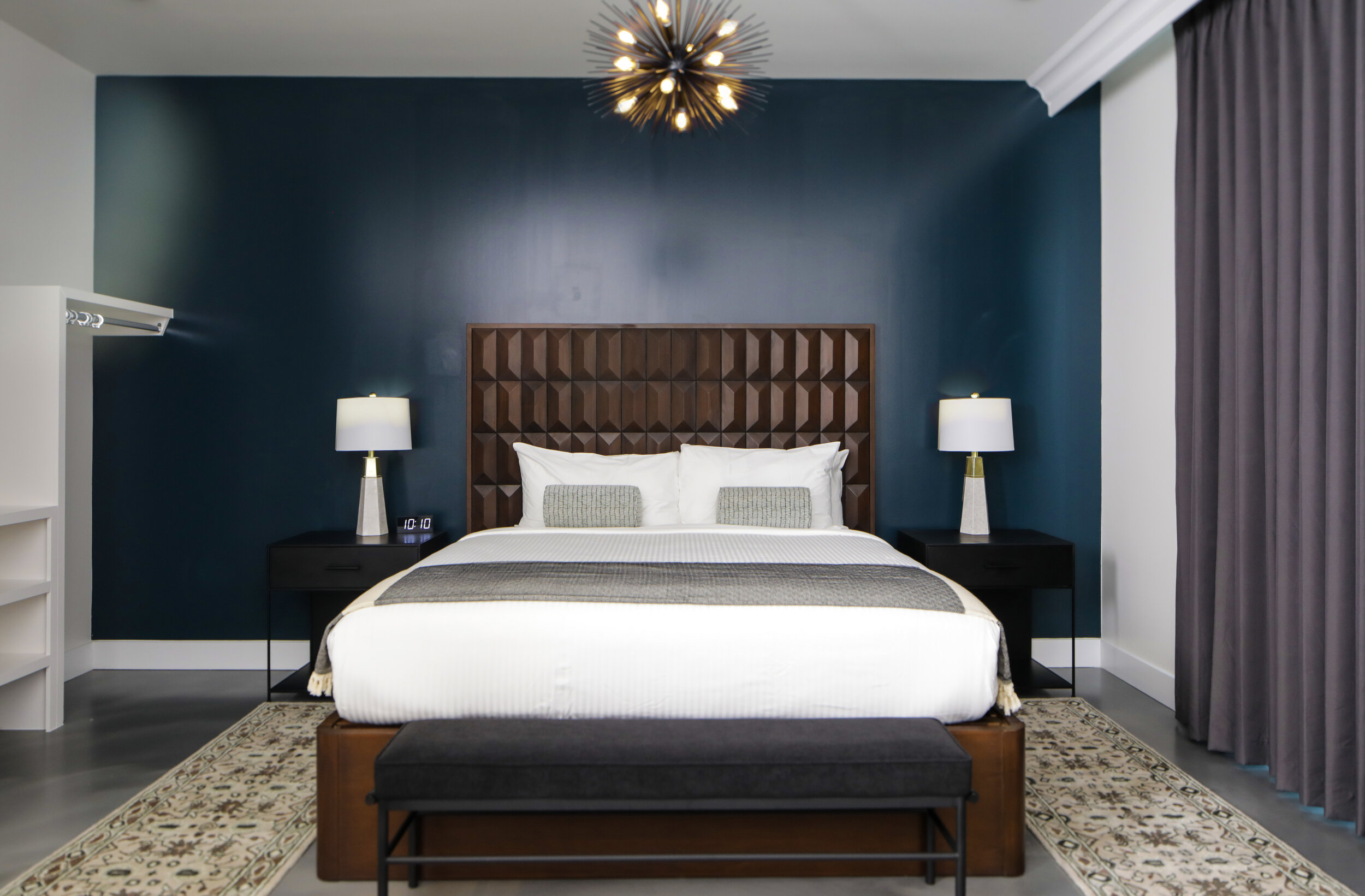 king bed with dark wooden headboard against dark blue wall