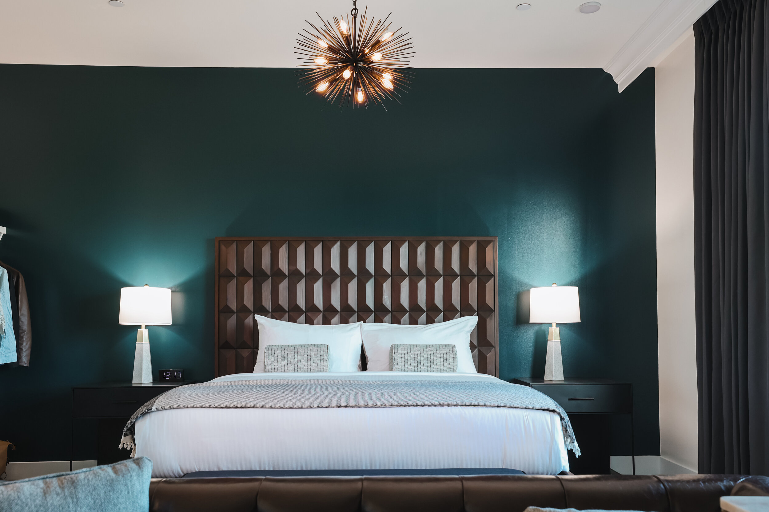 king bed with dark wooden headboard against dark blue wal