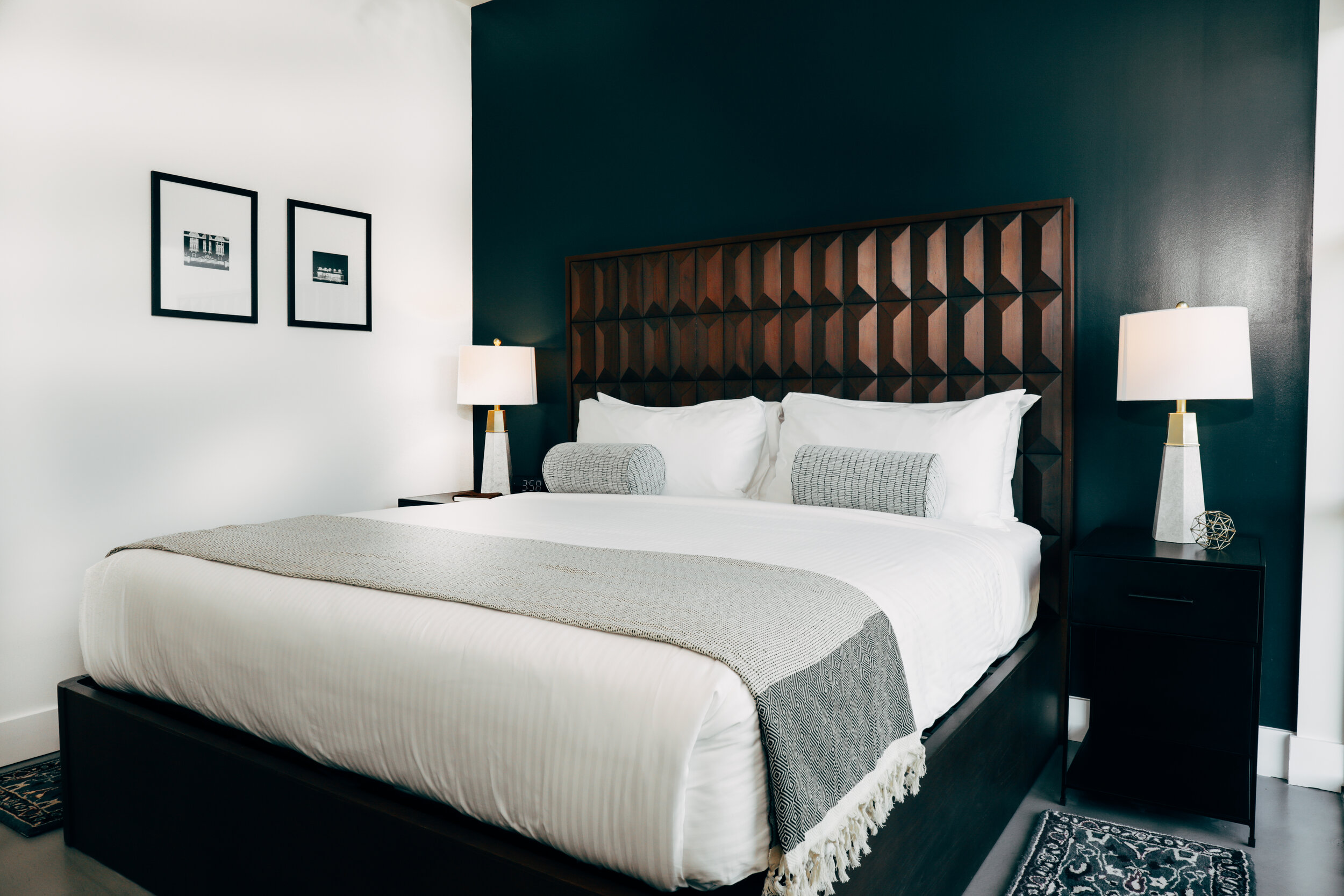 king bed with wooden headboard against dark blue accent wall (Copy)