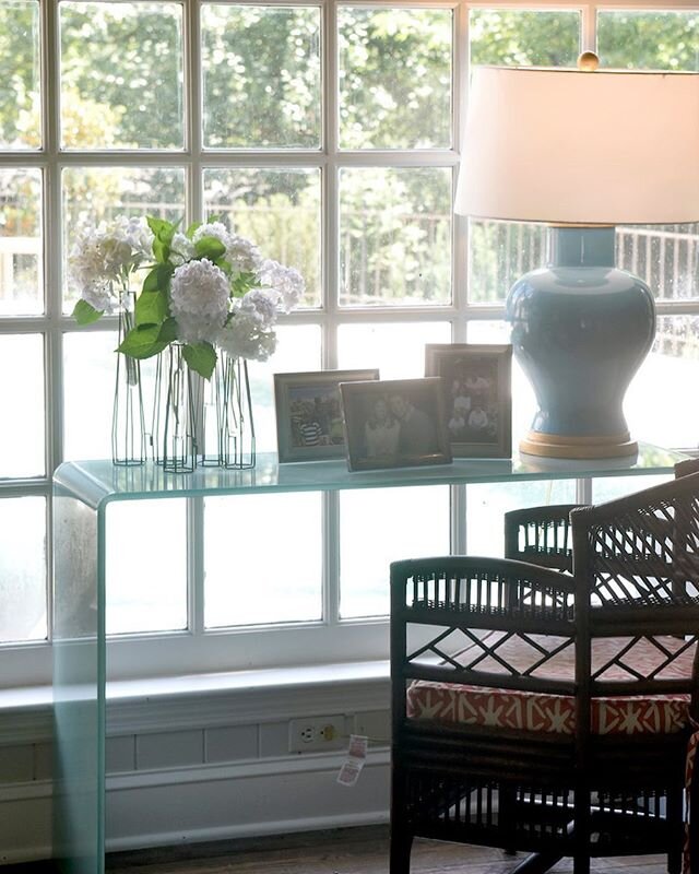 Time for a swim? We wanted to keep this large window open for a view of our client&rsquo;s beautiful pool. A clear glass console was the perfect solution. And, a ceramic lamp in a color with a nod to the water outside. We fitted a vintage bamboo chai