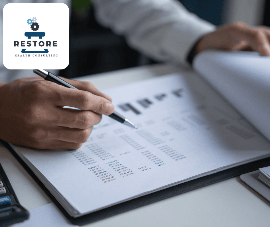 Notebook with business documents, hands in view, one hand holding a pen, Restore Health Consulting Logo