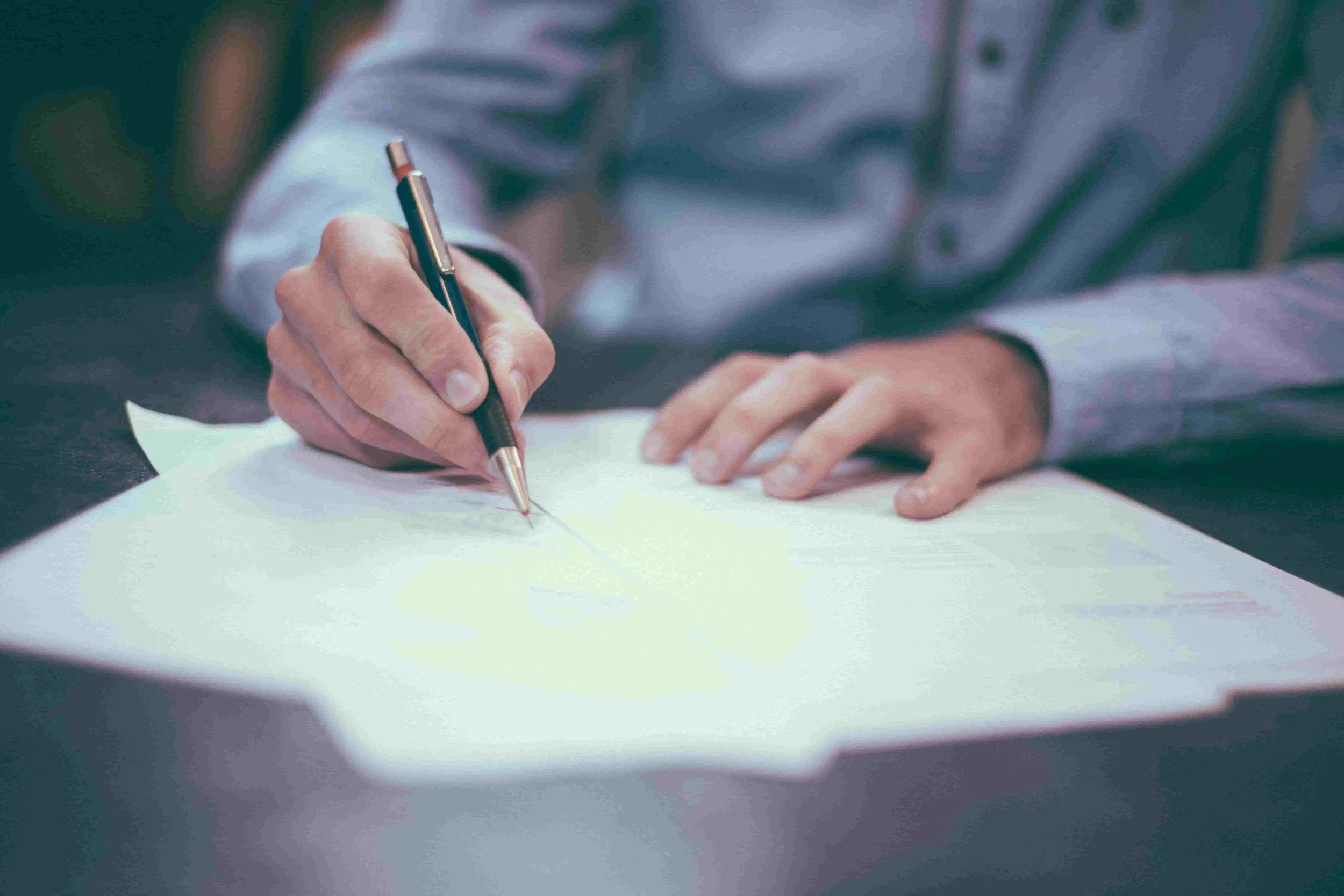 Business person writing on papers with a pen in shirt, to portray CQv strategy services