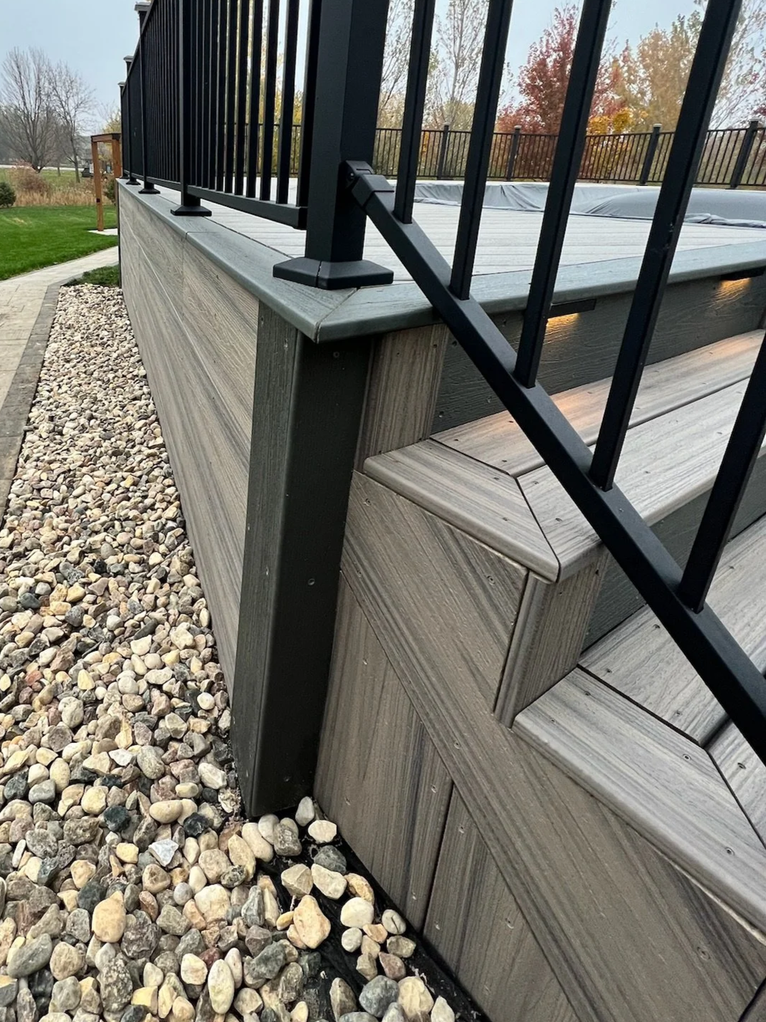close up of trex composite pool deck with picture framed stairs and black metal railing