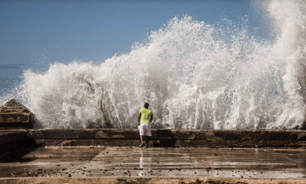 A man about to be washed over by a wave at el Malecón.