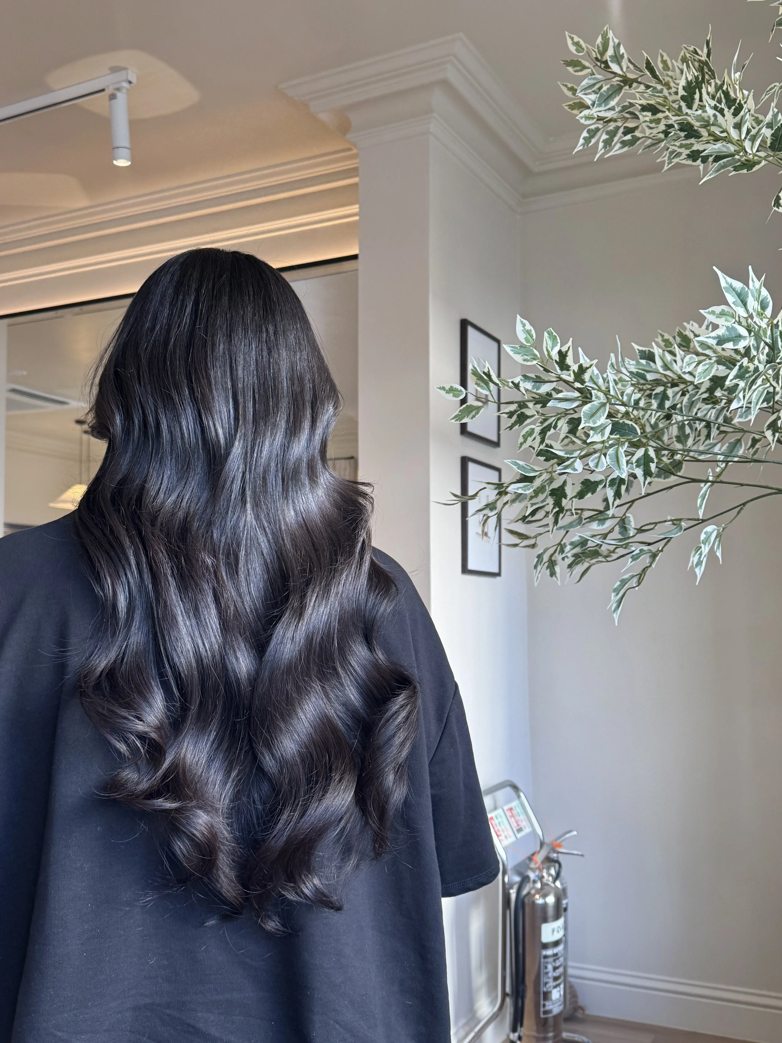 Long dark hair extensions styled in soft, natural waves at Carmen Walker hair salon