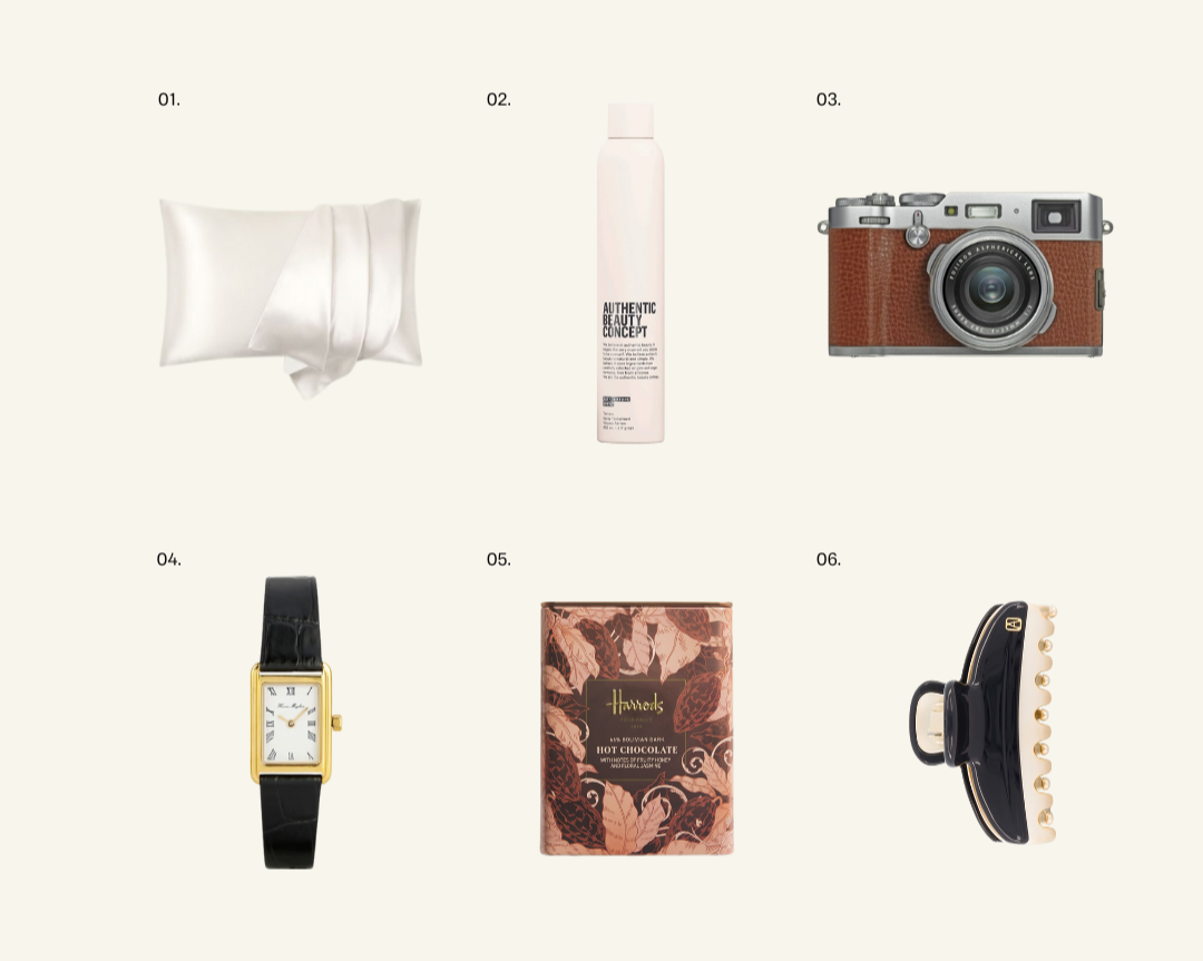 Flat-lay image featuring six curated gift items: a satin pillowcase, ABC Texture Spray, Fujifilm camera, classic watch, Harrods hot chocolate, and a navy claw clip — arranged as part of Grace’s Christmas gift guide.