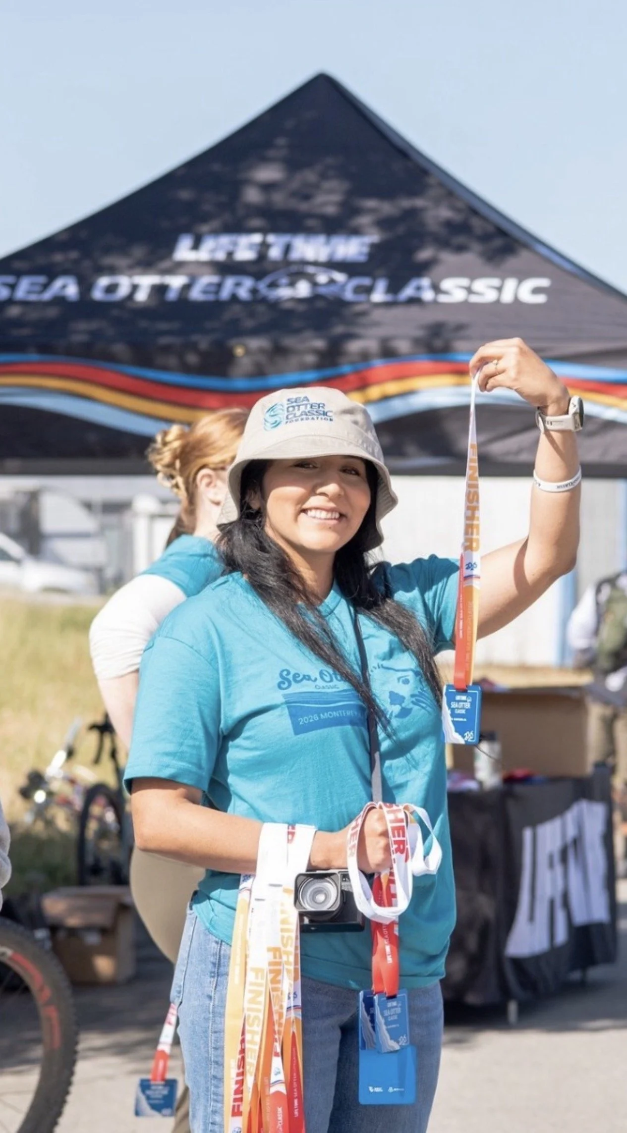 Female volunteer holding finisher medals at Sea Otter Classic