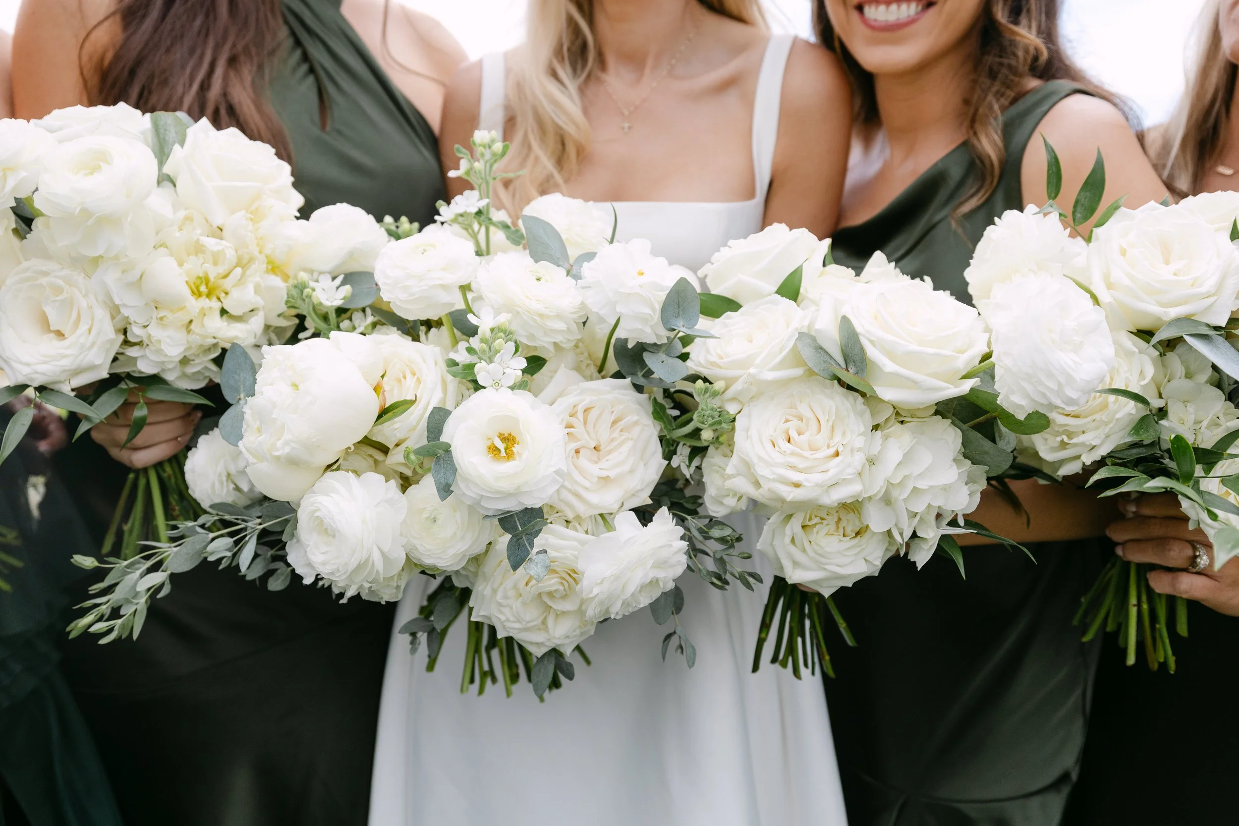Group of women holding white flower bouquets at a wedding or event.