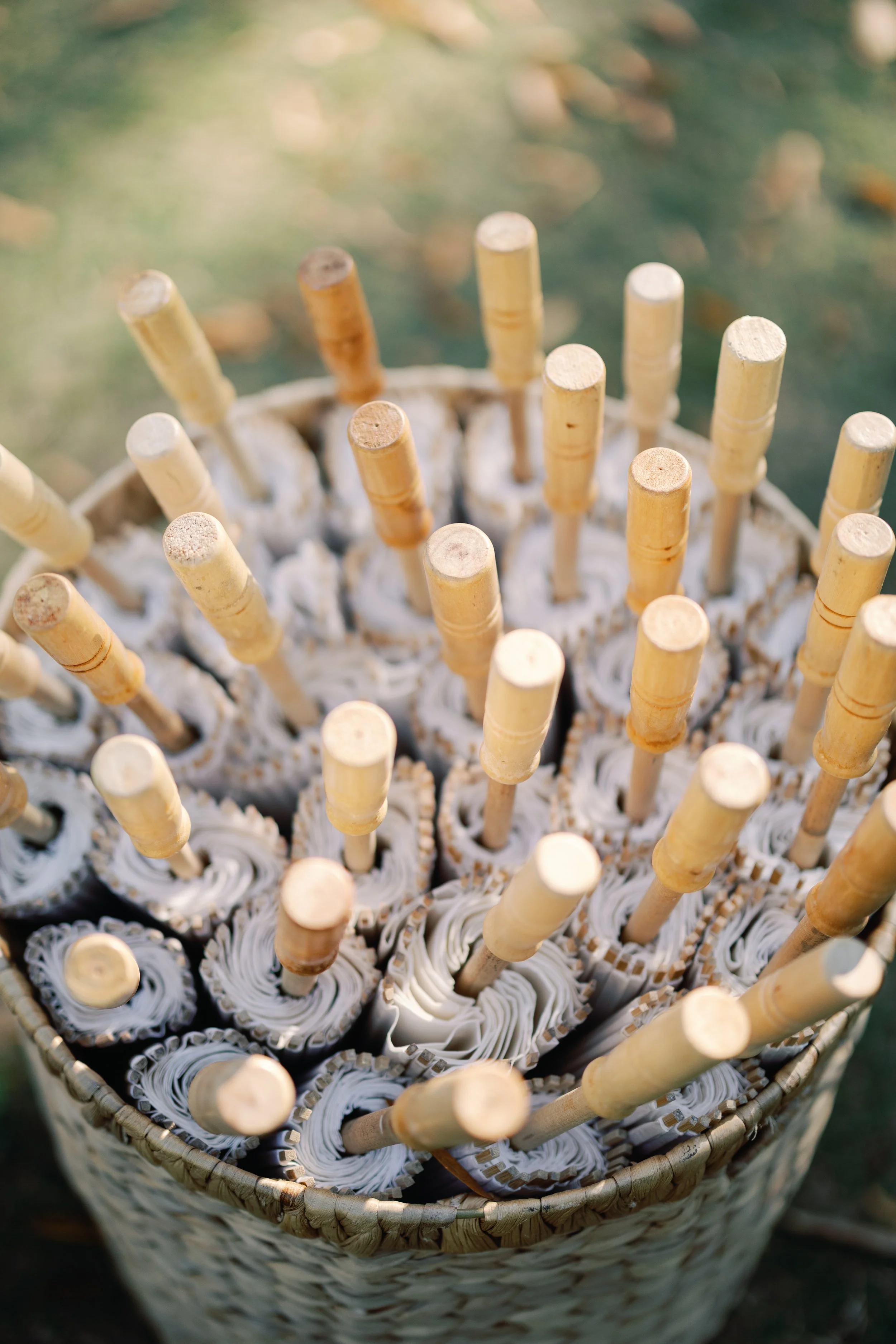 A basket filled with rolled paper scrolls, each with a wooden stick protruding from one end.