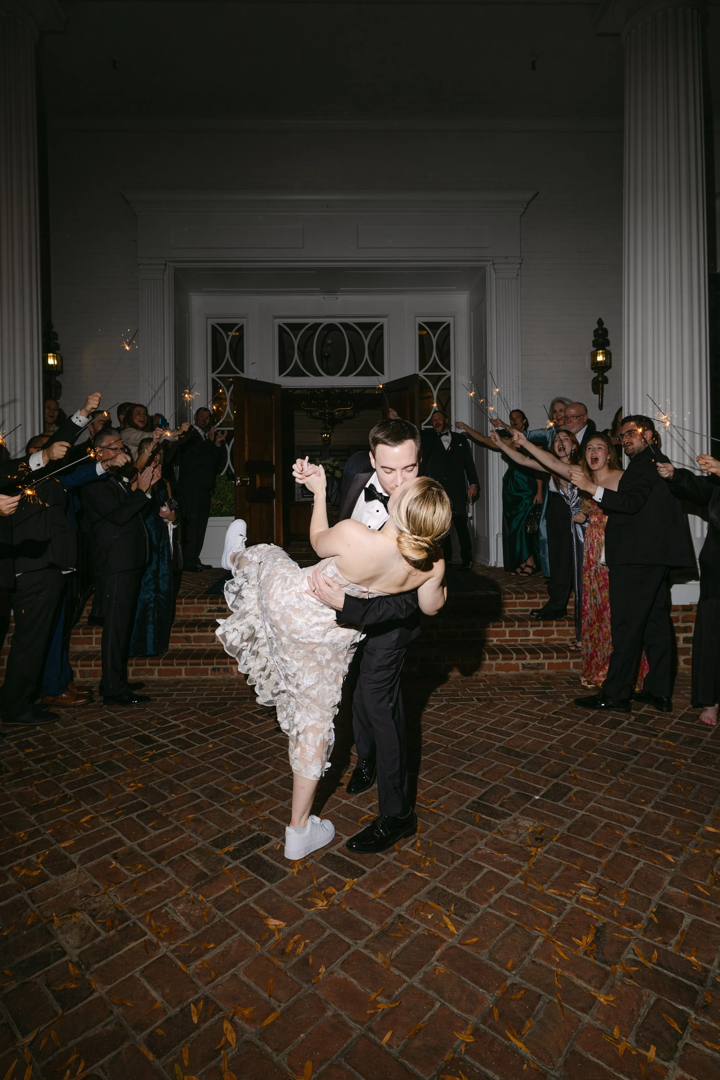 A wedding couple sharing a dance surrounded by guests holding sparklers outside a building.