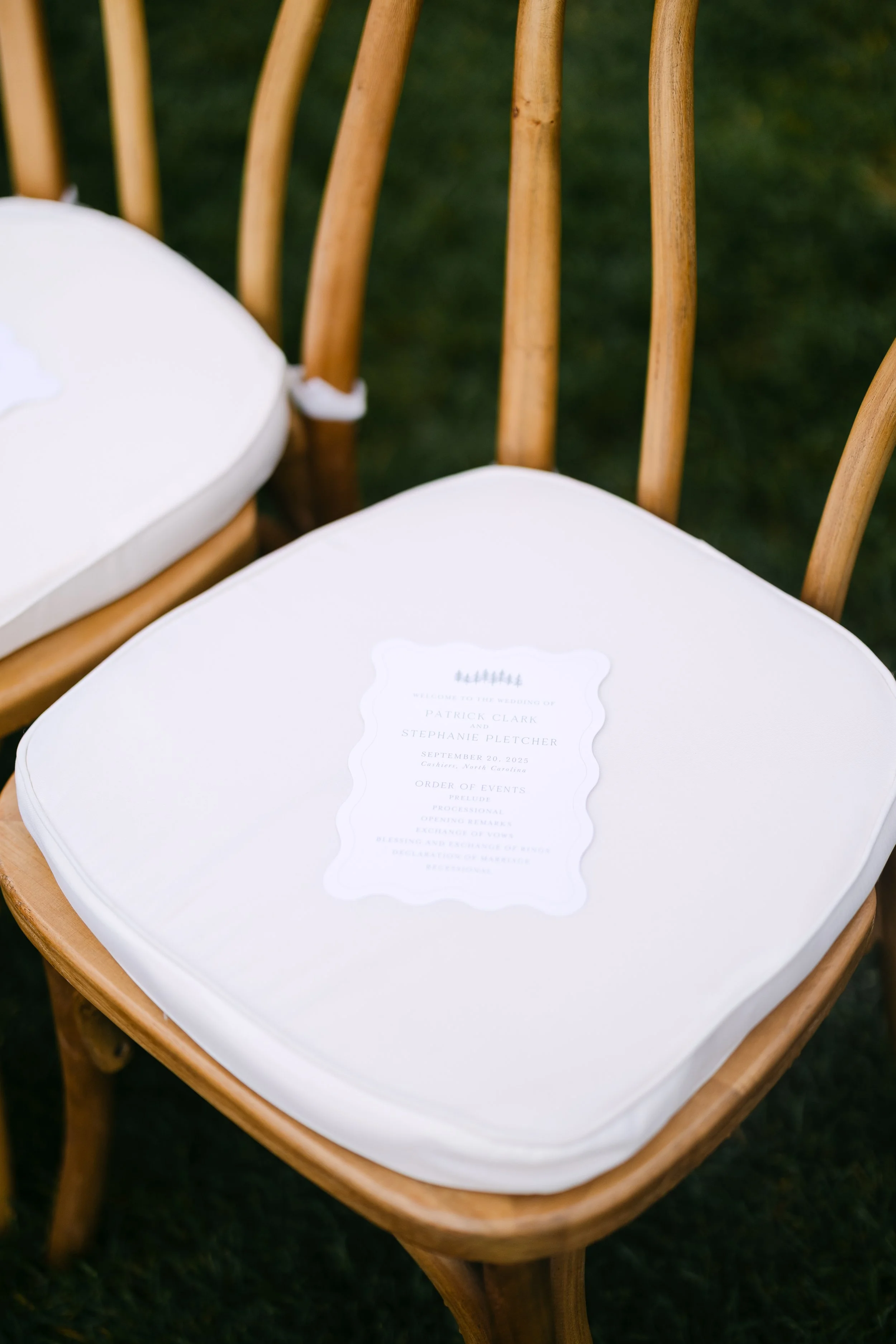 A wooden chair with a white cushion seat, holding a wedding program for Patrick Clark and Stephanie Pletcher on September 20, 2025.