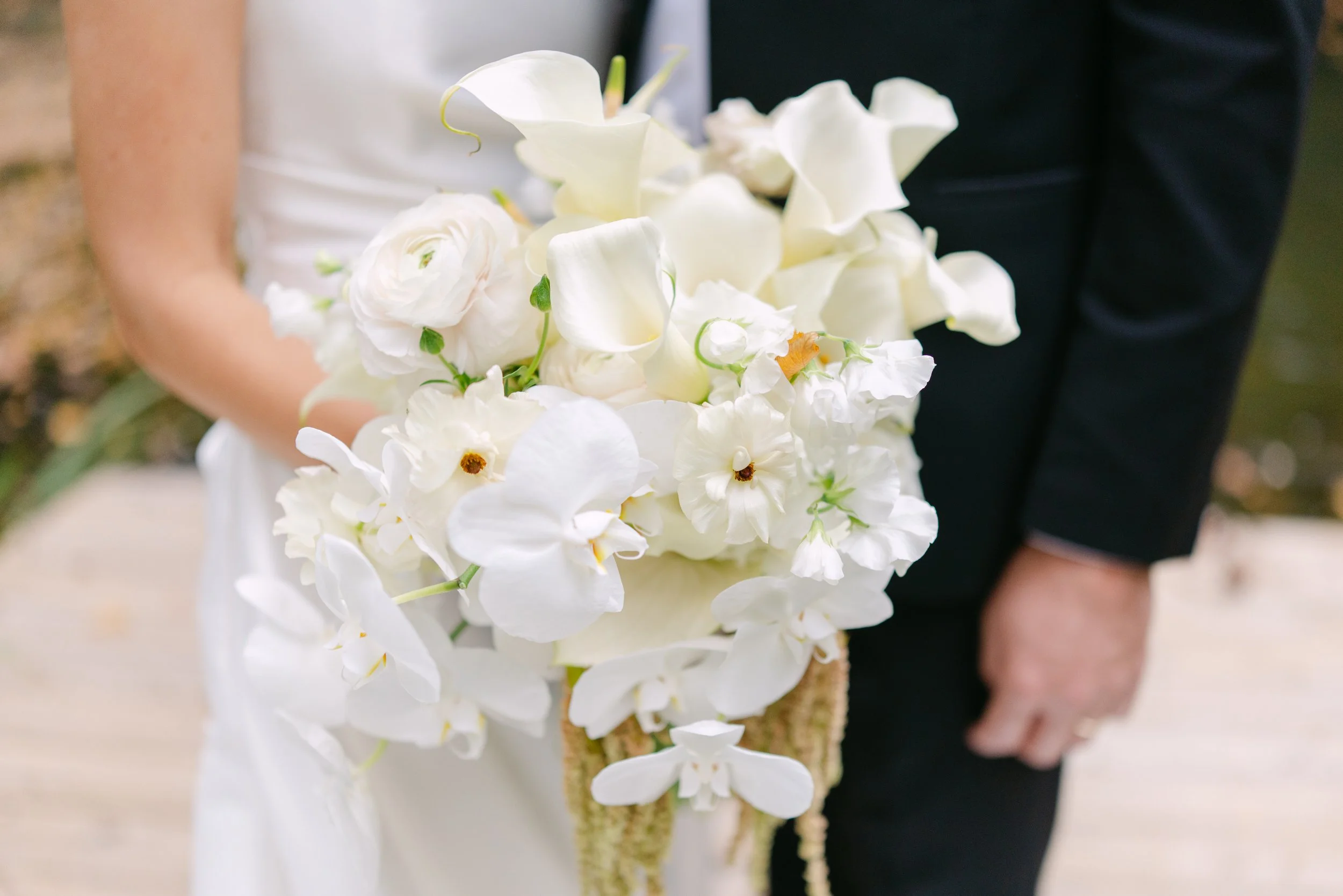Close-up of a lush white wedding bouquet held by a bride and groom