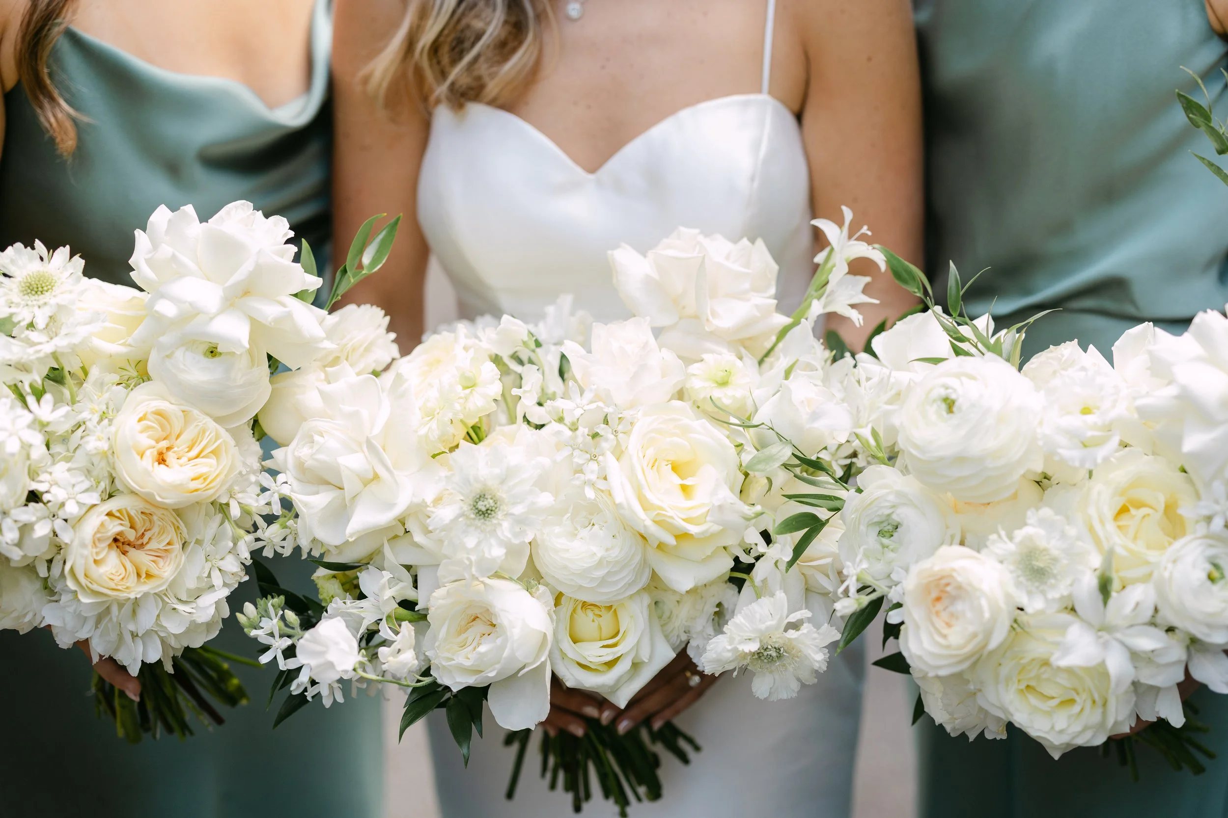 Close-up of women holding a bouquet of white flowers at a wedding.