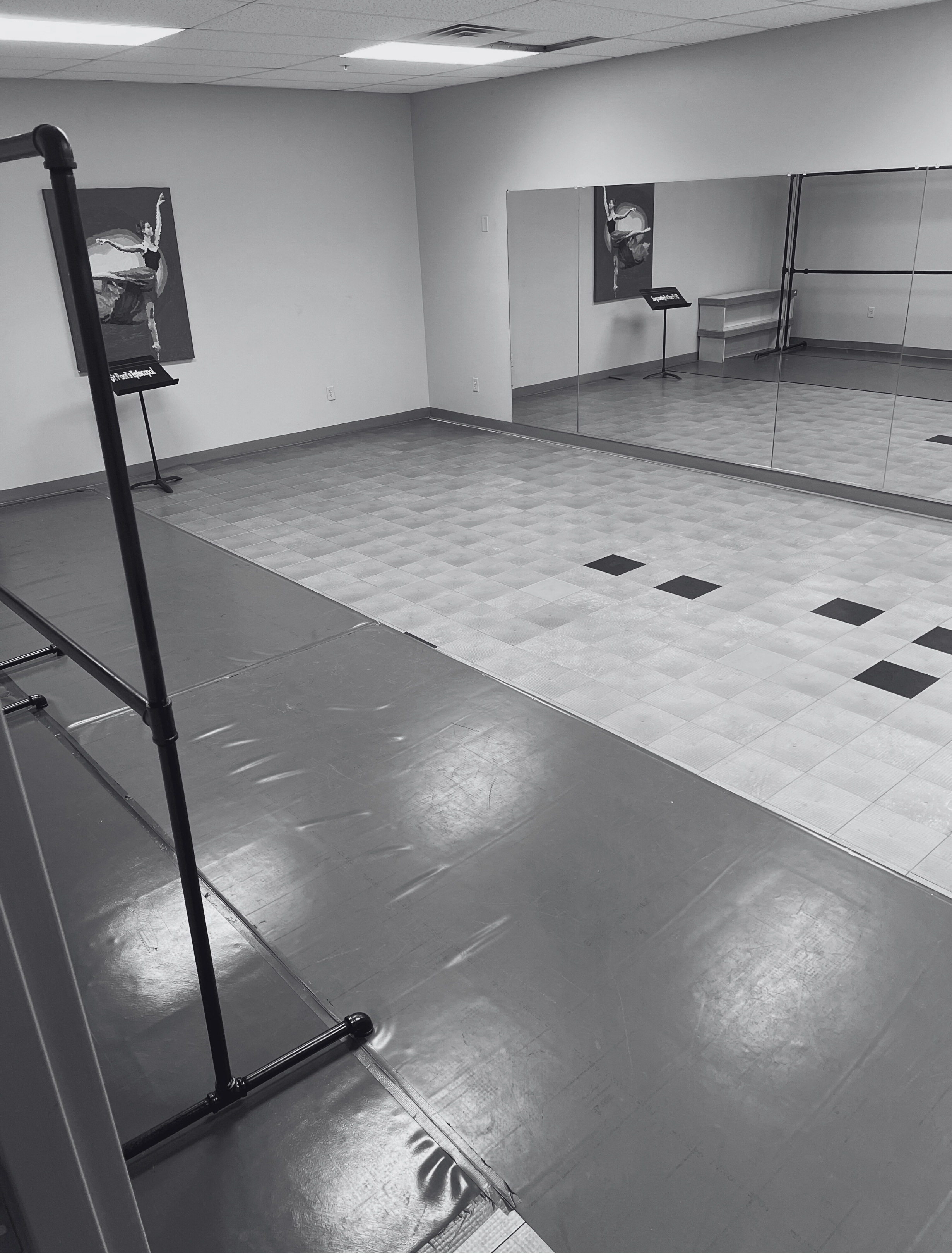 Dance studio with mirrors, ballet paintings, and flooring for dance practice.