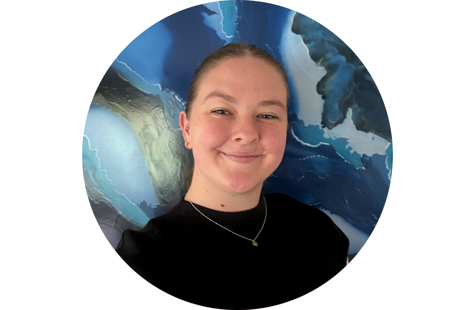 A young woman smiling in front of a large, colorful map of the world.