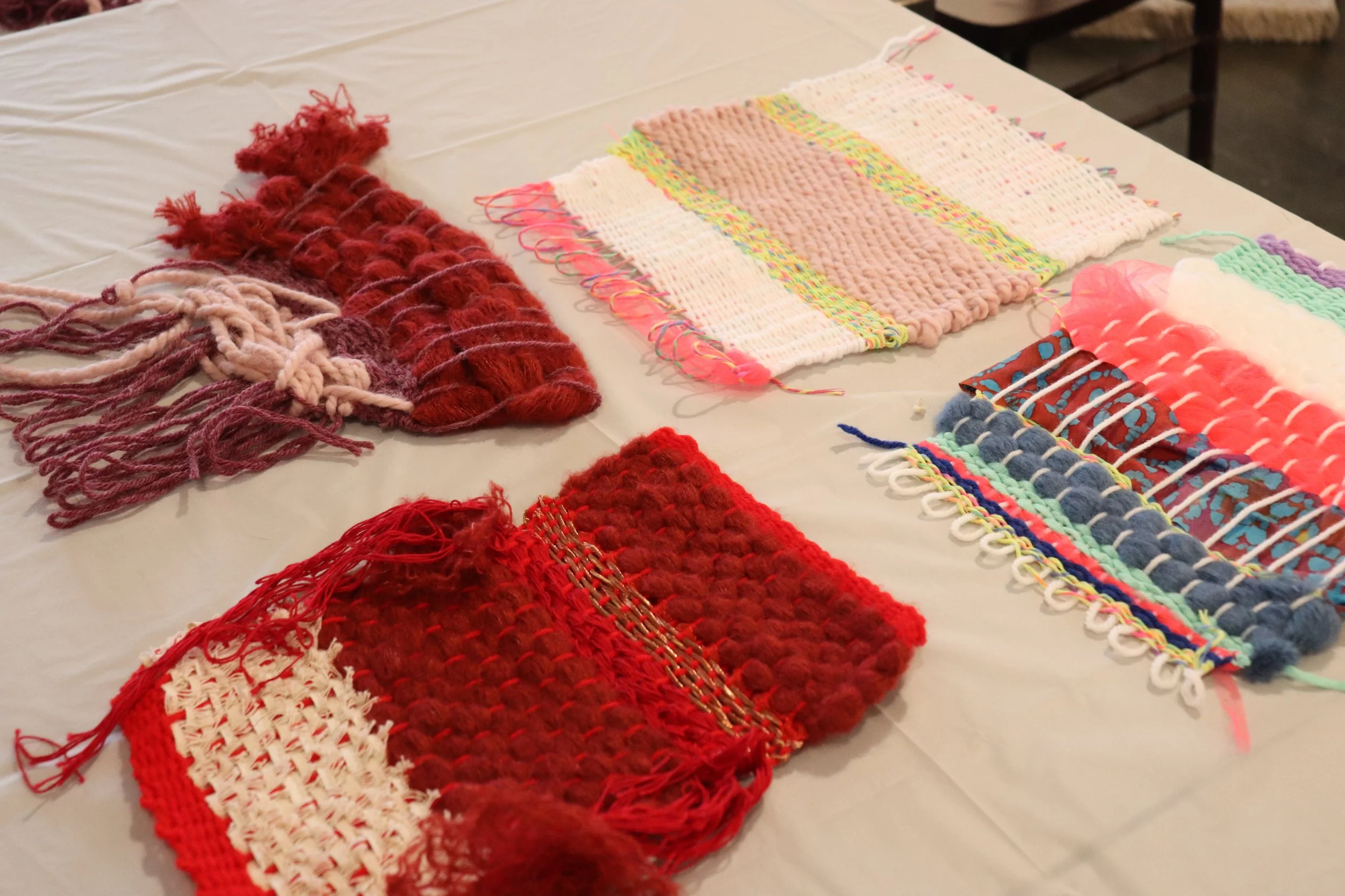 Image of four red and pink weavings on table.