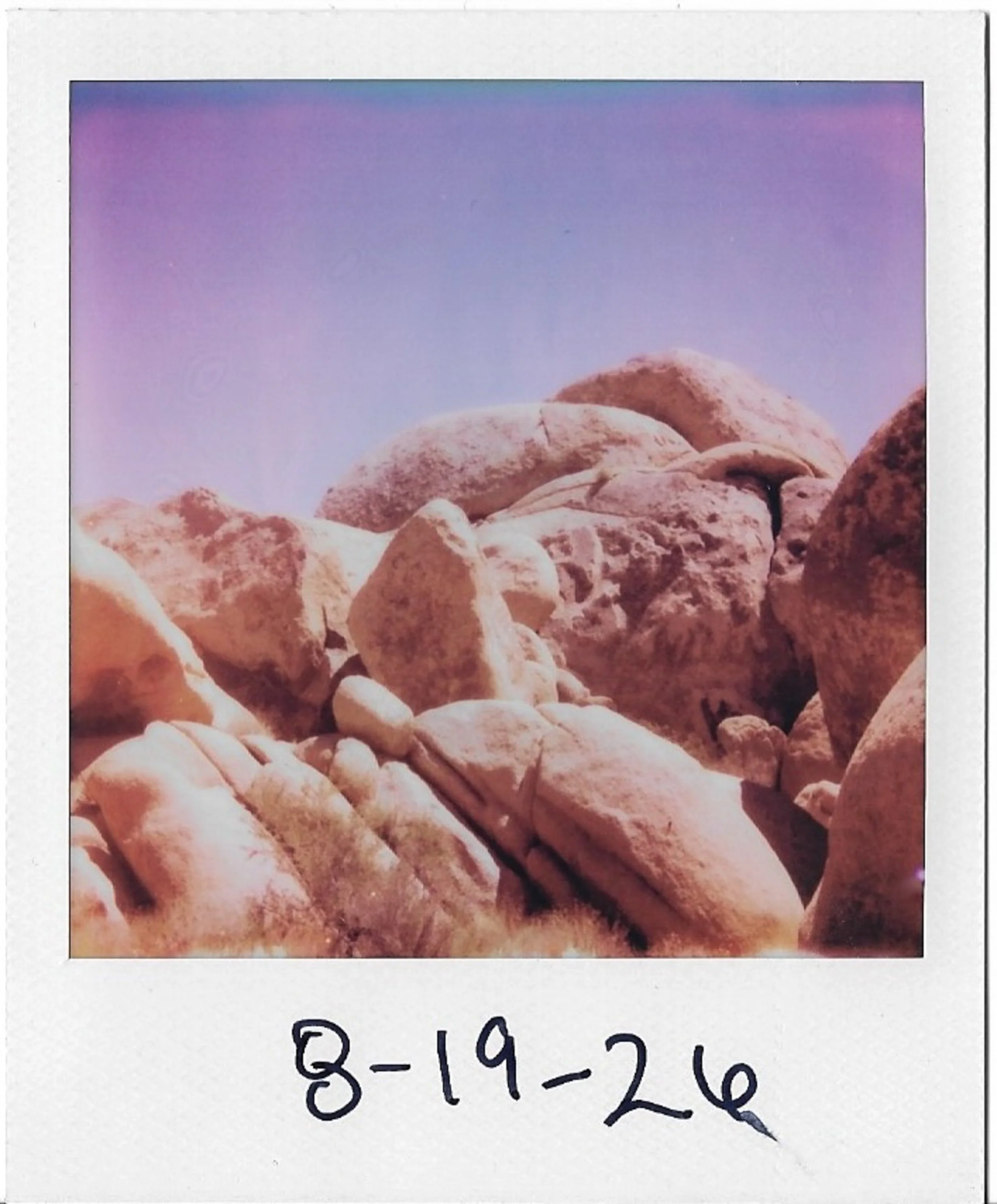 Close-up view of various rocks and stones of different shapes and sizes, with a handwritten label beneath them reading '8-19-26'.