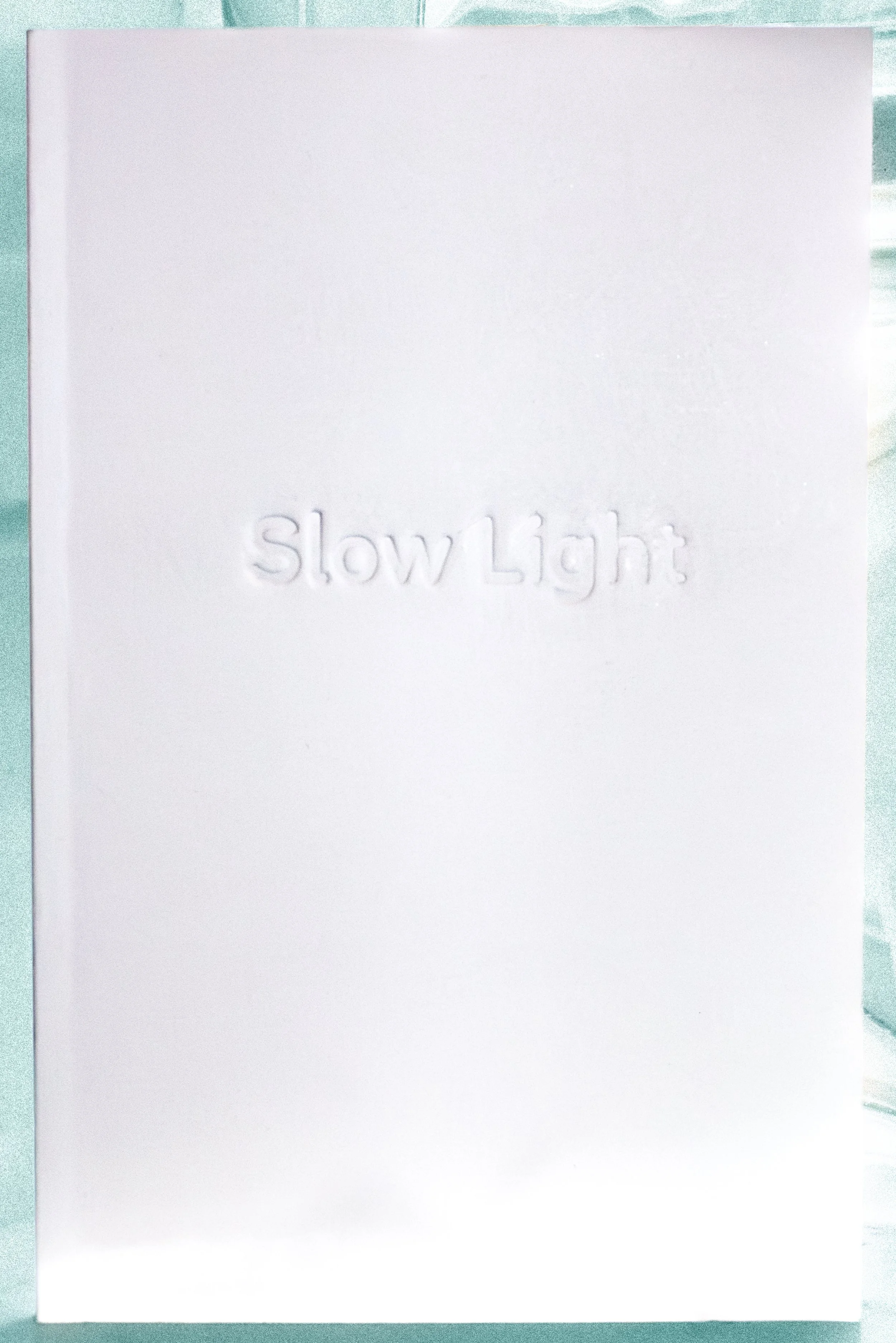 A white book with the embossed words "Slow Light" on the front.