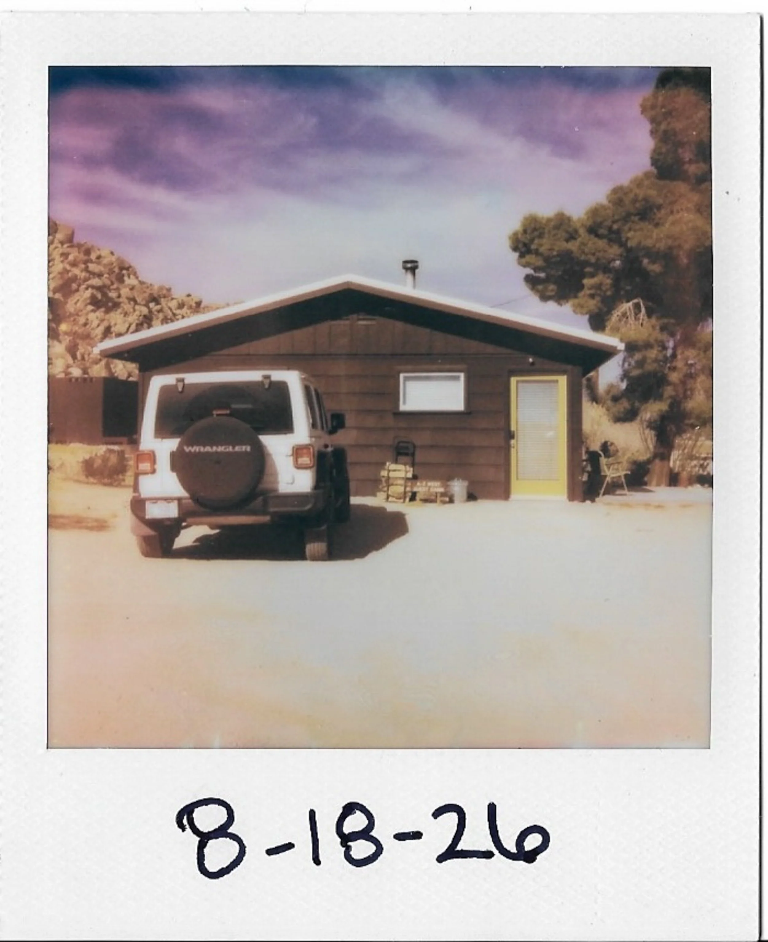 Polaroid photograph showing a house with a car in front and a date written at the bottom: 8-18-26.