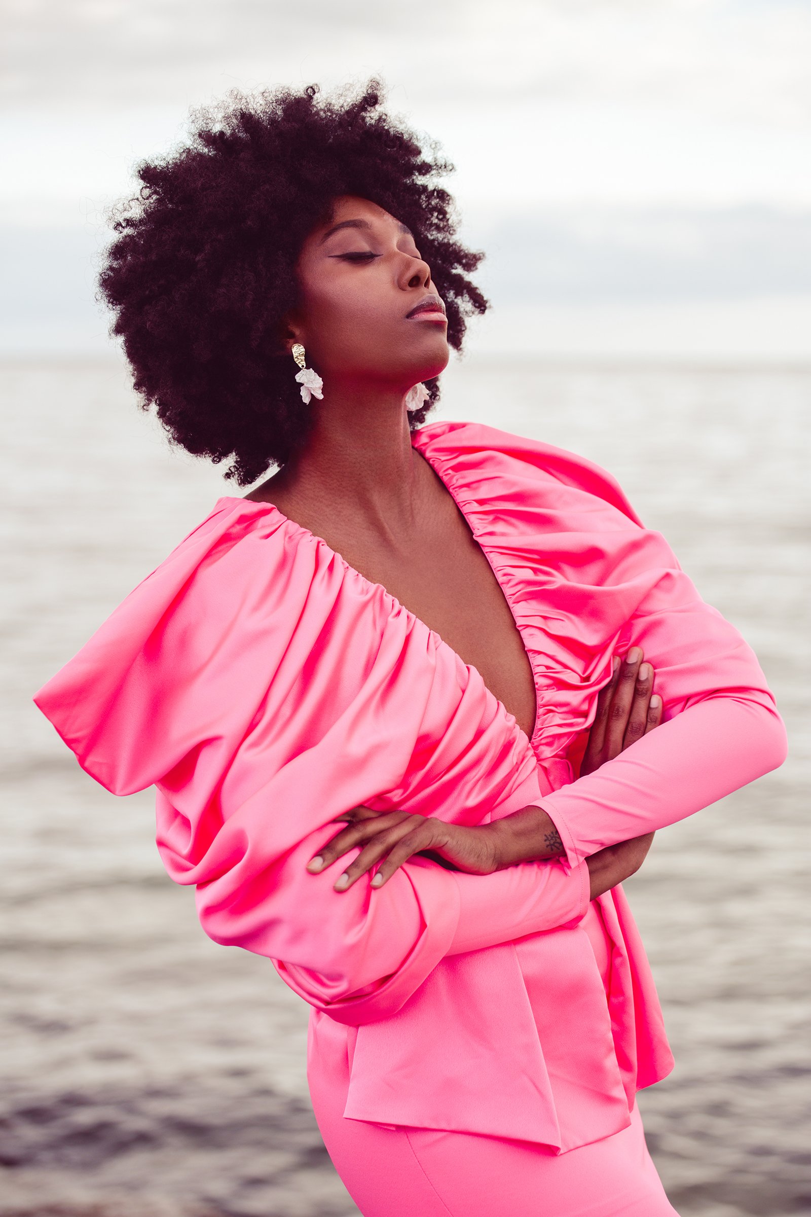 Person wearing a bright pink dress by the ocean