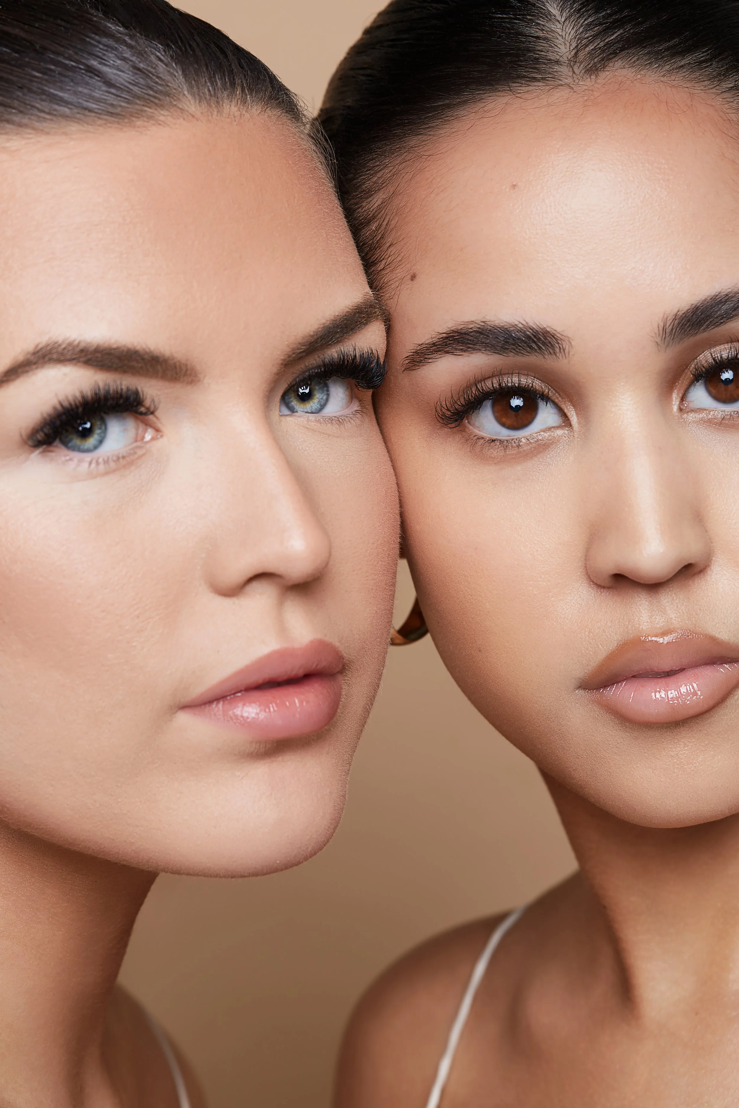 Close-up of two women with clear skin and glossy lips, facing forward.