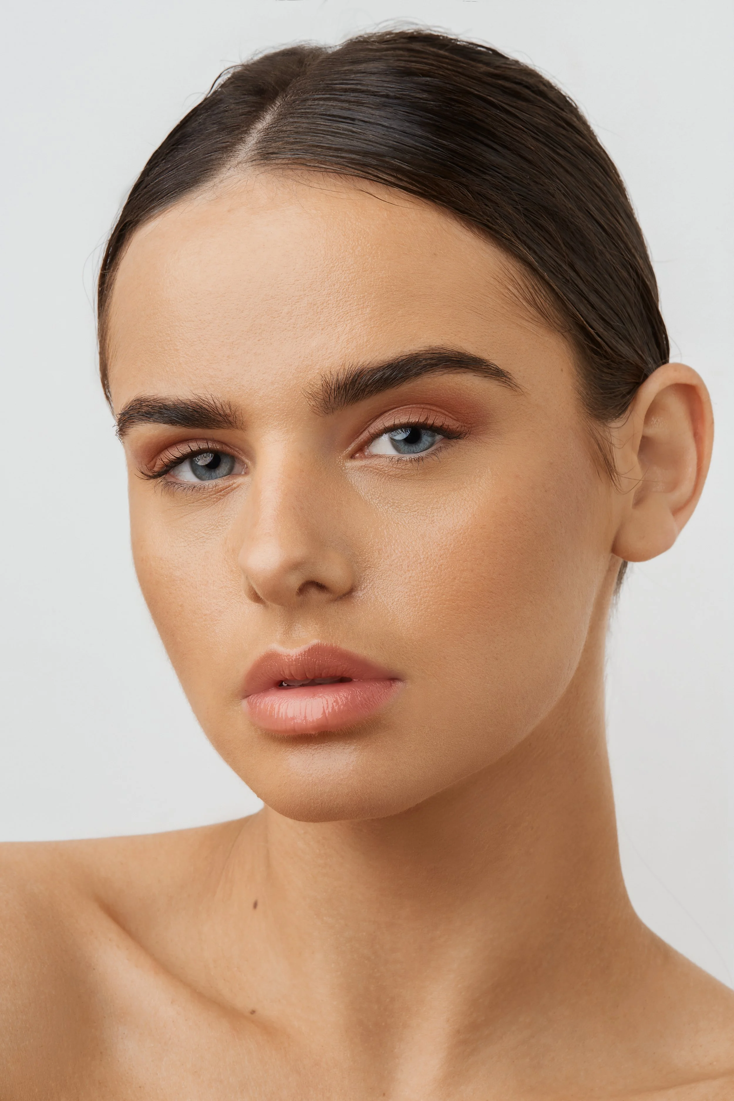 Portrait of a woman with slicked-back hair and natural makeup