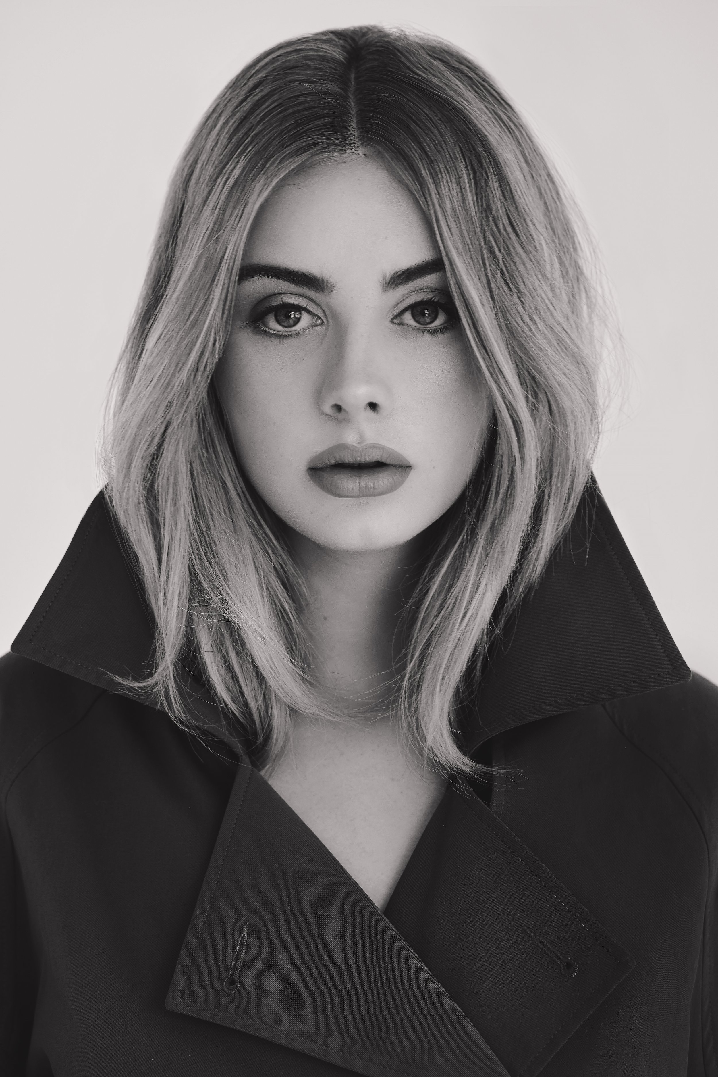 Black and white portrait of a woman with medium-length hair wearing a dark coat.