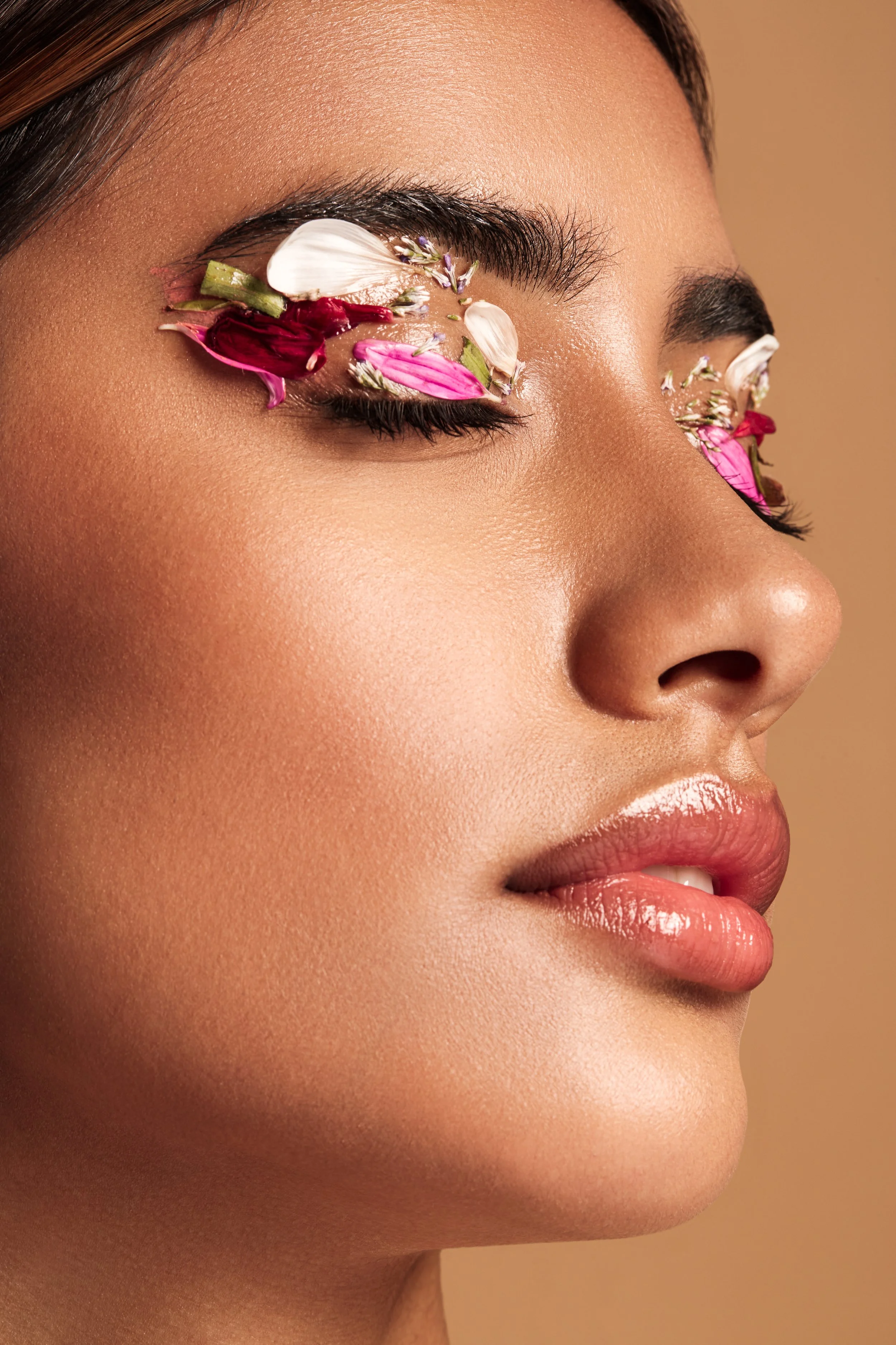 Close-up of a woman's face with flower petals on her eyelids
