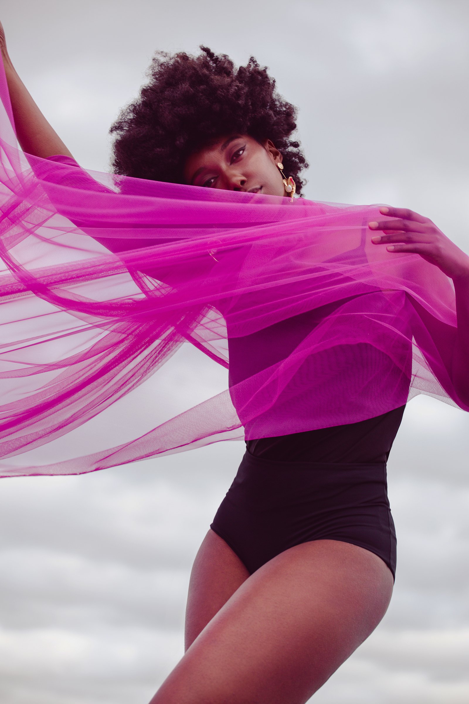 Person wearing a pink sheer fabric and a black leotard outdoors.