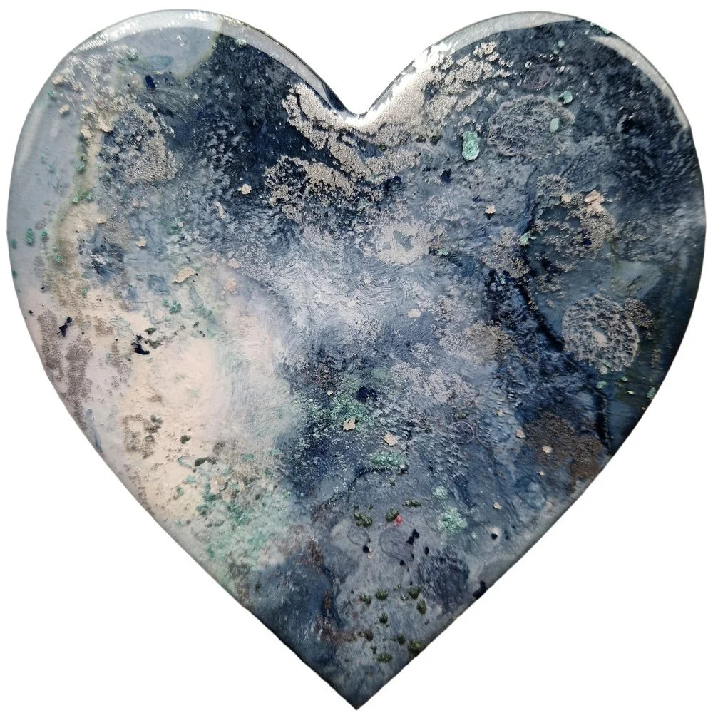 A metallic heart-shaped object with a textured, marbled surface in shades of blue, gray, and white.