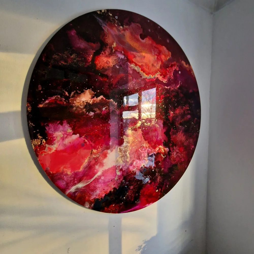 Round abstract painting with swirling reds, pinks, black, and gold colours. Original bespoke abstract resin ink and mixed media artwork created by artist Katie Alize, based in UK, Essex, London.