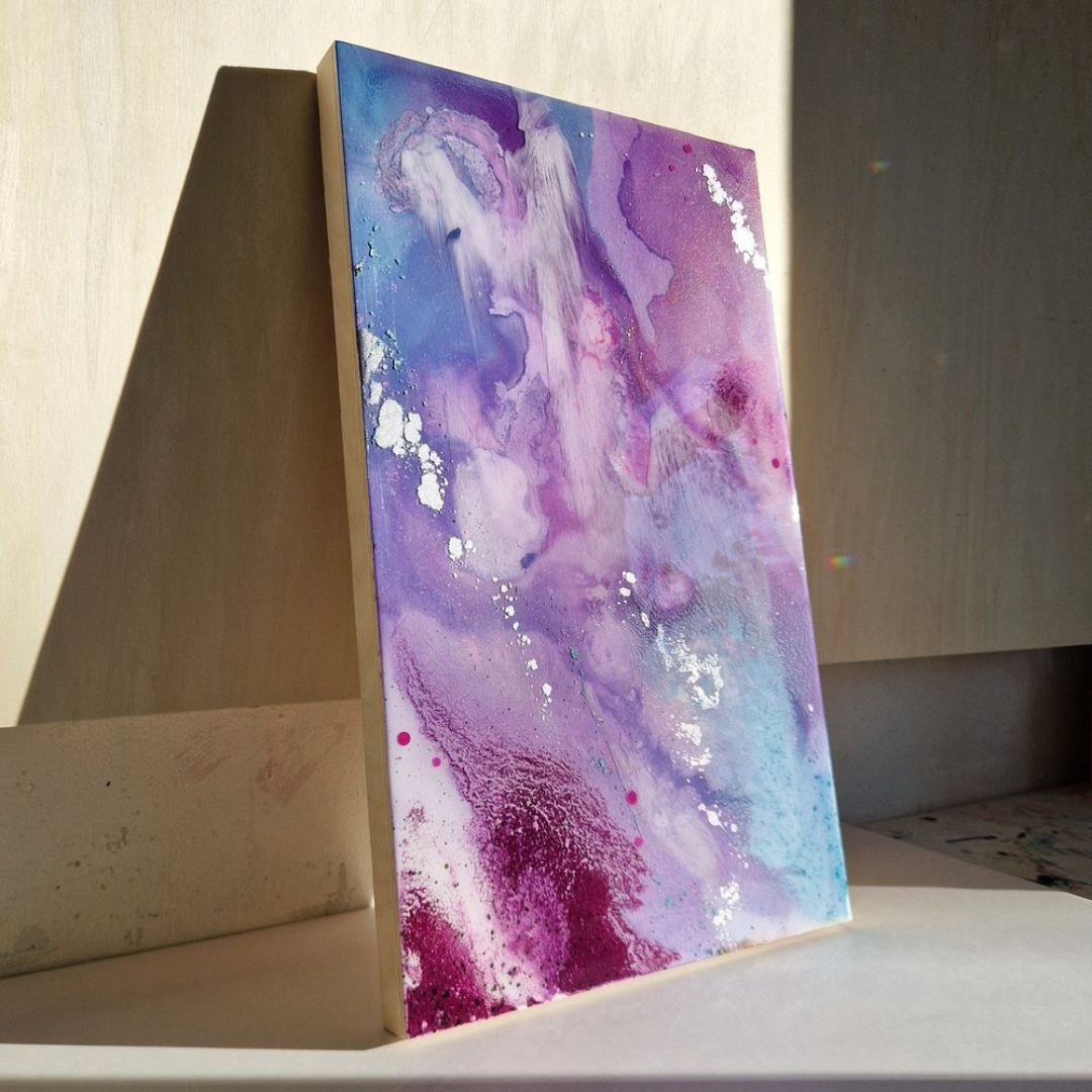 Abstract resin art painting with purple, pink, blue, and white hues leaning against a wall, with sunlight casting a shadow. Created by UK resin artist Katie Alize Art.